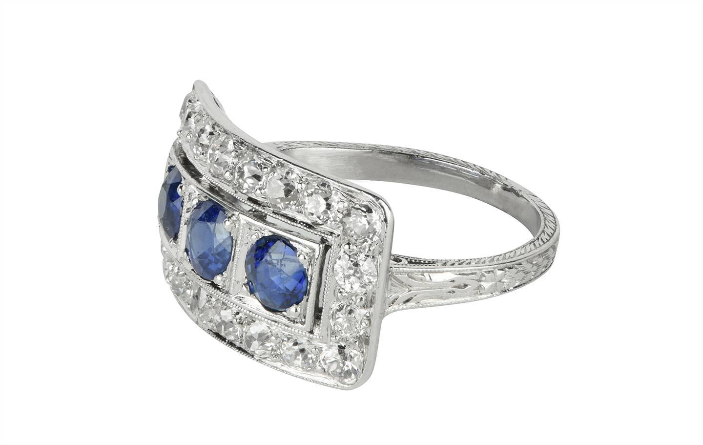 A beautiful sapphire and diamond platinum ring from the Art Deco period.  There are three old round cut sapphires set in the center, with a single row of old European cut diamonds surrounding.  the sapphires have a total weight of 1.00cts, and the