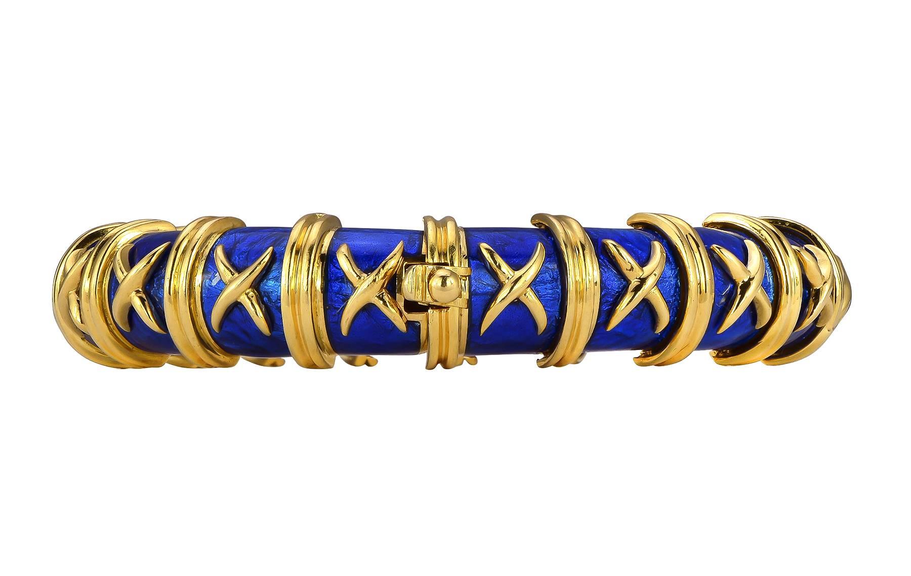 Tiffany & Co. Schlumburger bangle, crafted in 18k yellow gold and enrich with electric blue enamel, accented with gold X’s and double piped borders surrounding the entire bracelet. The bracelet measures one half inch in width and four tenths of an