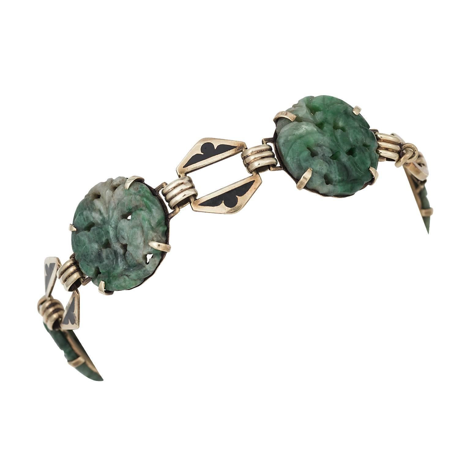 Carved jade and black enamel  14 karat yellow gold bracelet.  The jade is made into five stations, with each depicting a floral carving, linked together with black enameled gold.

Hallmark:  14K
Signature:  WL
Length:  7.00 inches 