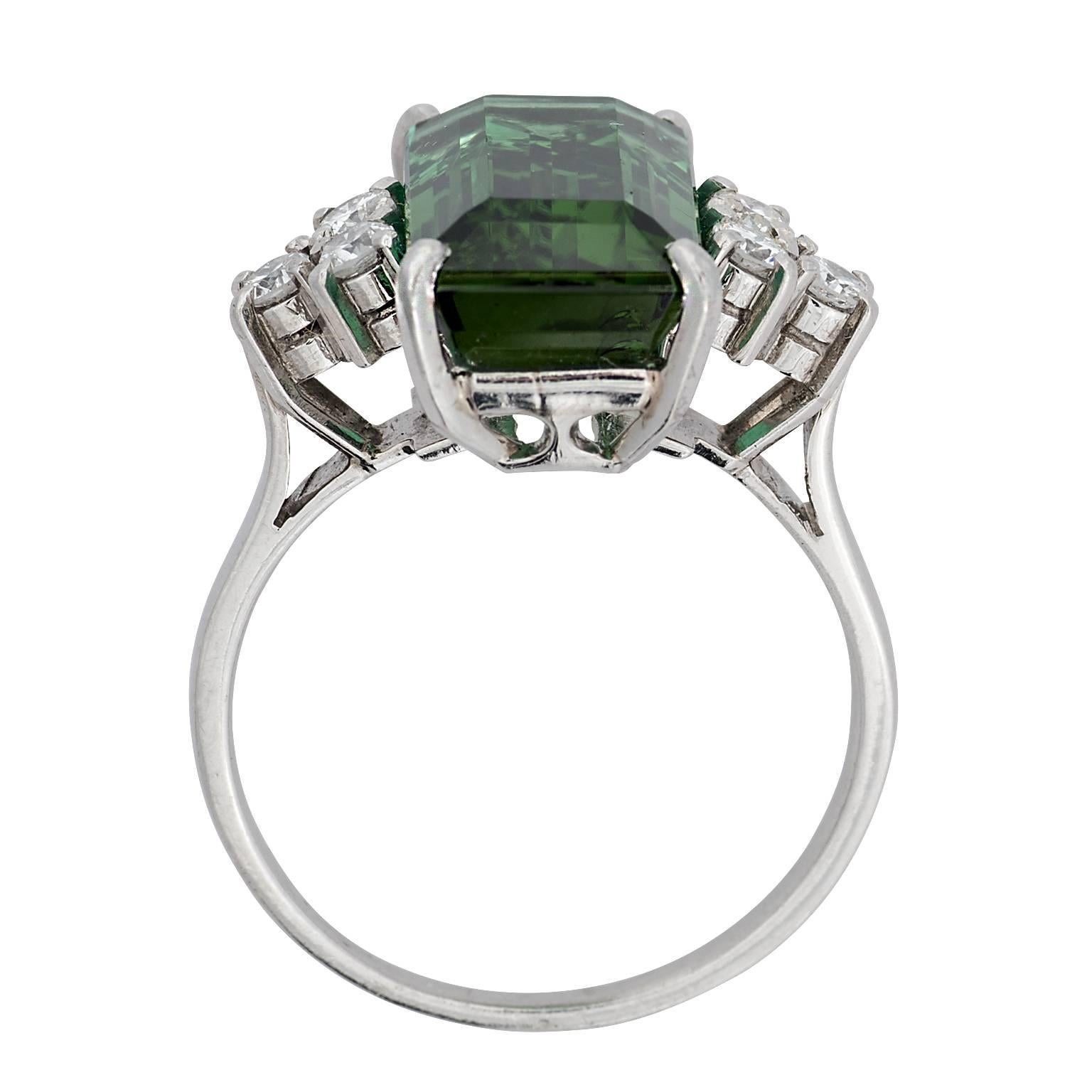 4.02 carat emerald cut green tourmaline and round brilliant diamond platinum ring.  There are six round brilliant diamonds totaling 0.24 carats.  The tourmaline is set in a four prong basket.

**Currently a finger size 7.25