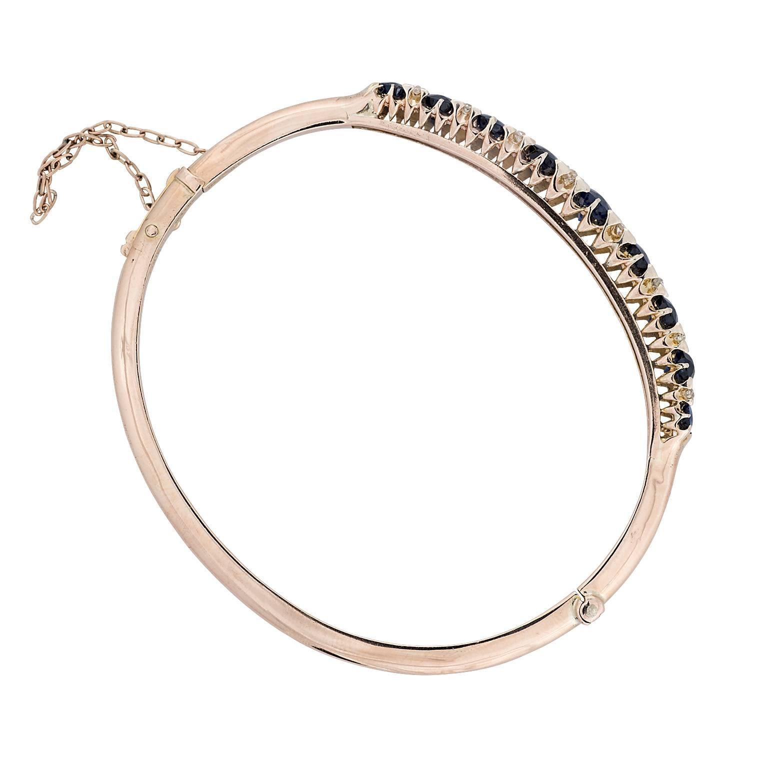 Victorian era natural sapphire and diamond 14k yellow gold hinged bangle bracelet.  The nine oval sapphires have a total weight of 3.60 carats, with two old european cut diamonds between each sapphire.  The diamonds have a total weight of 0.50