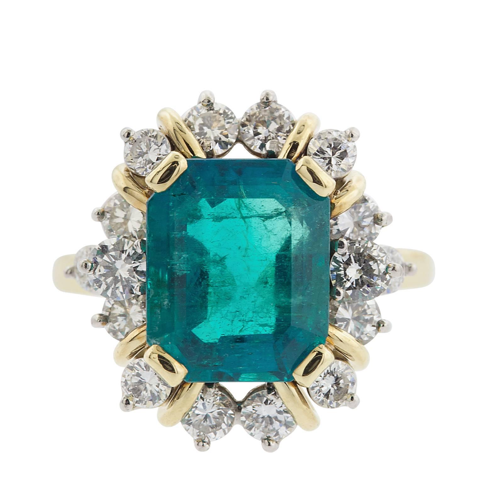 A natural 4.21 carat emerald cut Colombian emerald, surrounded by 1.10 carats in round brilliant diamonds, in 18 karat yellow and white gold.  The emerald has an American Gemological Laboratories Report, stating the origin, and other features of