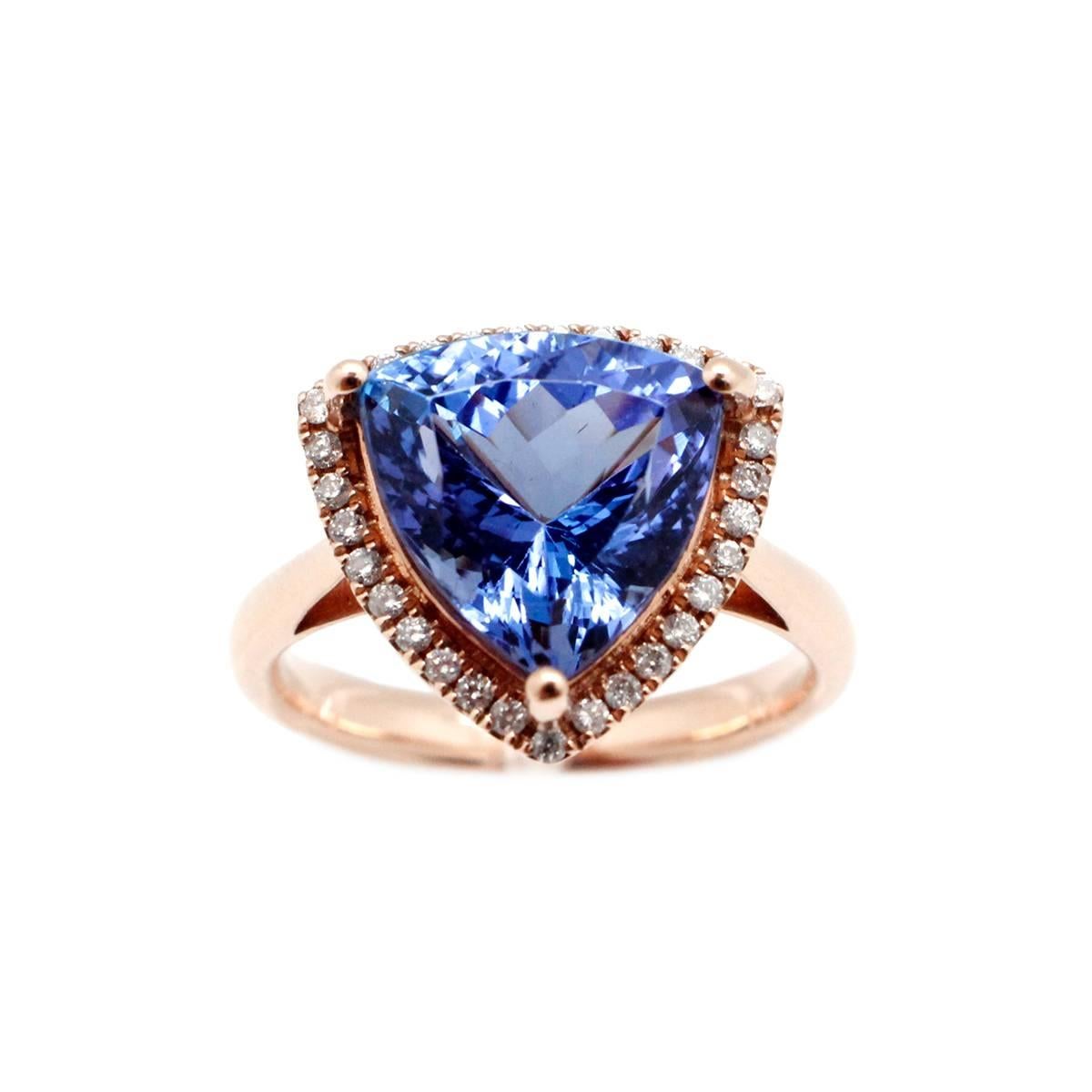 This custom ring produced by Aristocrat Jewelry features an absolutely stunning center Natural Vivid Violetish Blue Trillion Cut 6.07 Carat Tanzanite with 30 diamonds on the border of the center stone totalling .31 Carats. The surrounding diamonds