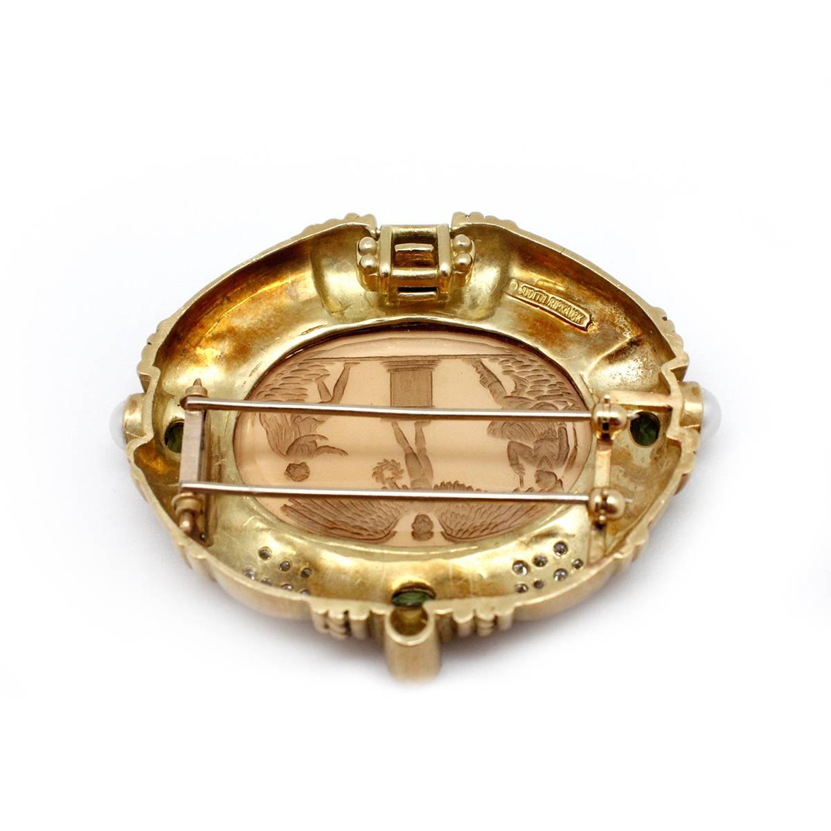 This pin is crafted in 18kt yellow gold by famous designer Judith Ripka. At it's center piece is an expertly hand carved oval intaglio citrine stone that measures 35mmx25mm. In addition the pendant features two pearls, four bezel set peridot stones