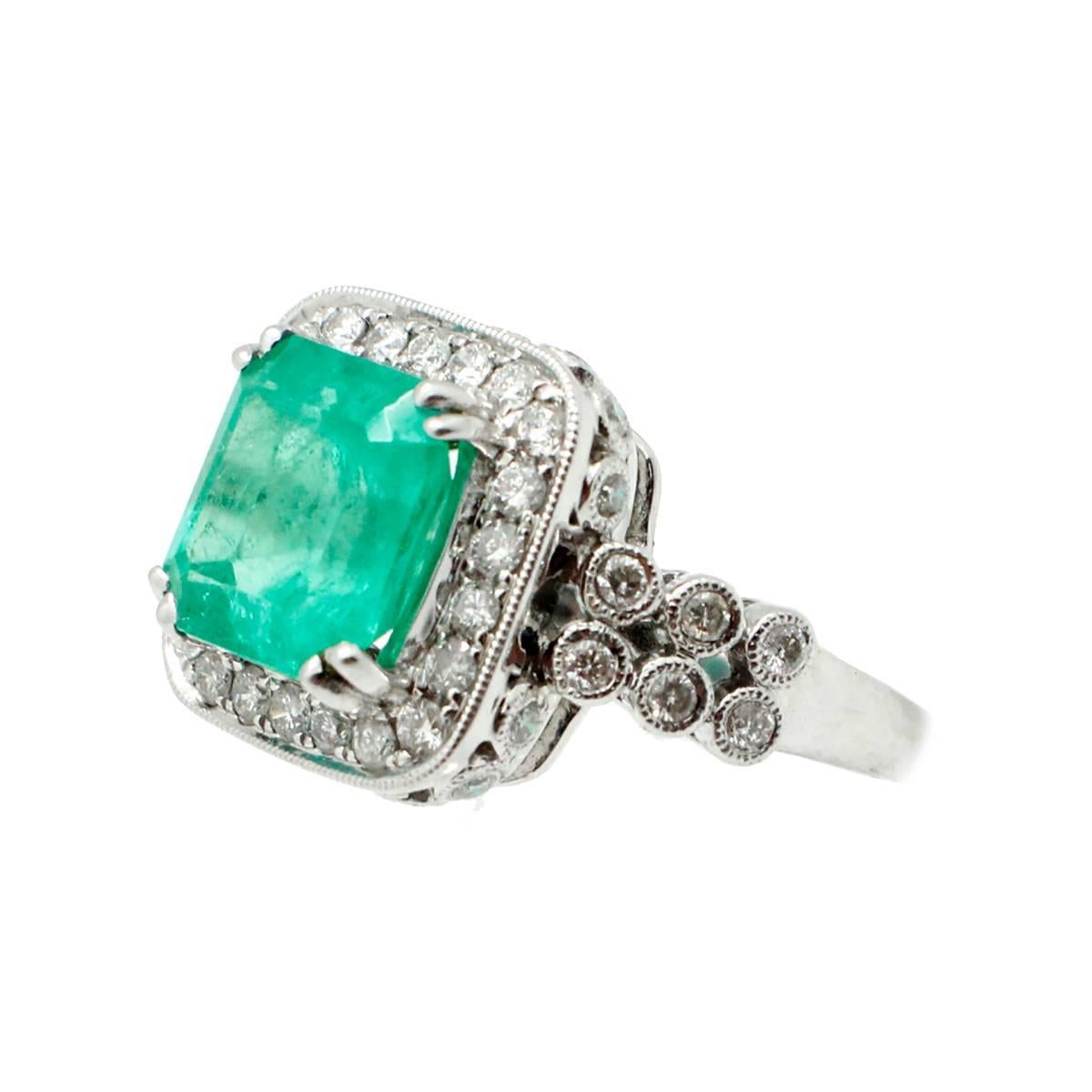 This gorgeous ring features a center stone emerald weighing approximately 4.13 carats. Surrounded by a capturing halo of round brilliant diamonds for an additional weight of 1.50 carats. The diamonds are graded H in color and VS in clarity. Hand