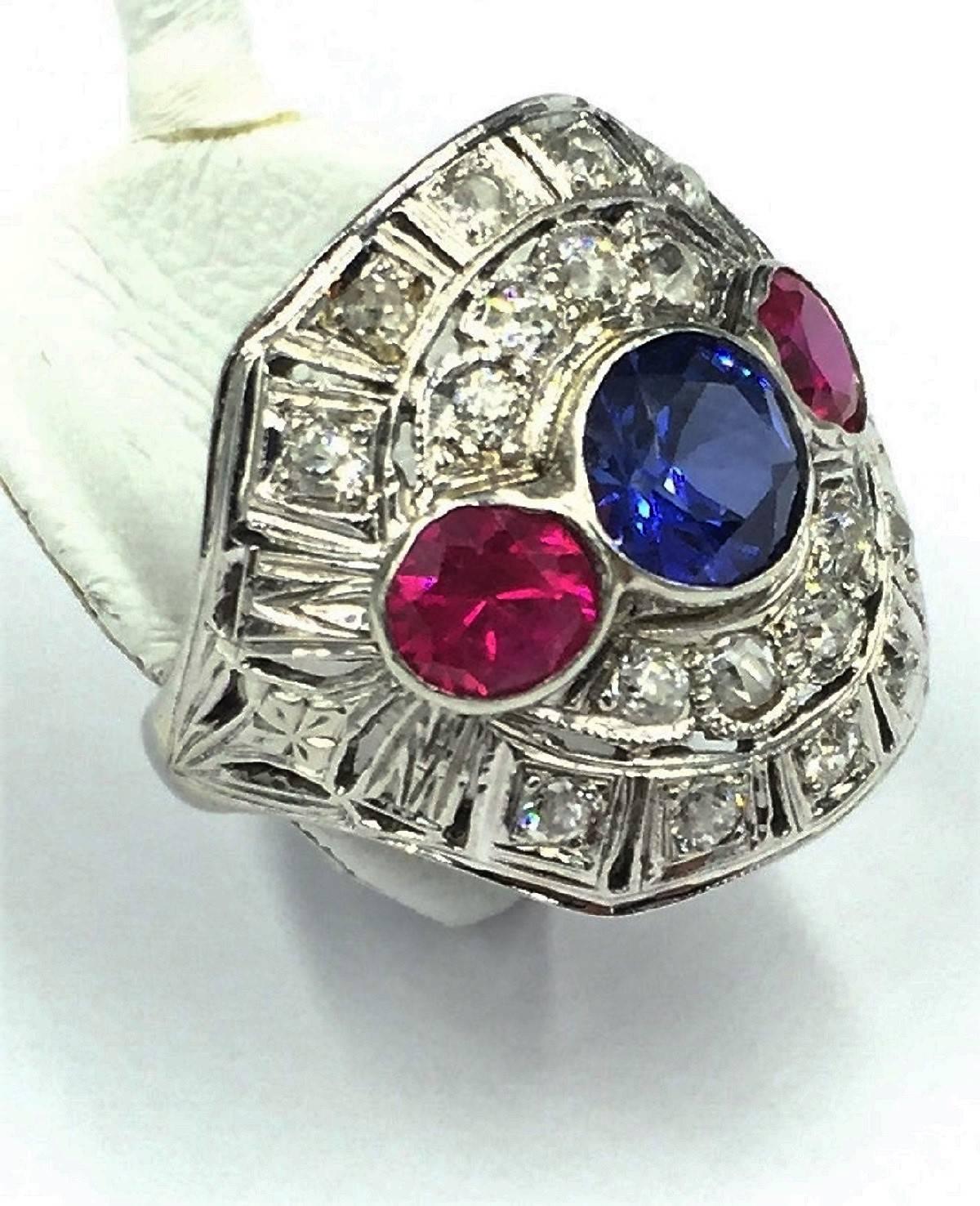 This ring is a true one of a kind from the Art Deco period. The bold colors, fine work, and handcrafted ring is beautiful beyond words. This Art Deco 18kt White Gold Ring features two show stopping .60 carat each rubies on the sides totalling 1.20