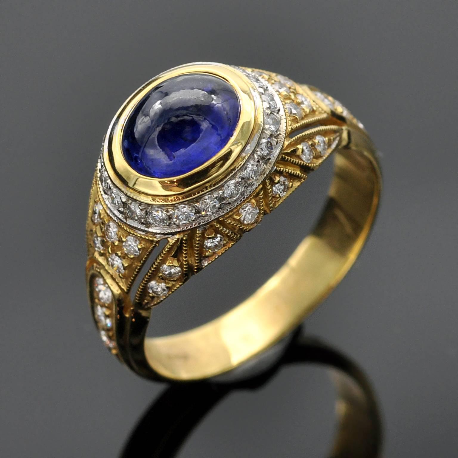 Atemberaubender zweifarbiger gewölbter Ring. In seiner Mitte ein glänzender blauer Cabochon-Saphir. Die Millegrain-Fassung und die Ziselierarbeit verleihen dem Ring eine raffinierte Note.

Saphir ± 2 Karat
Diamanten : 0,50 Karat