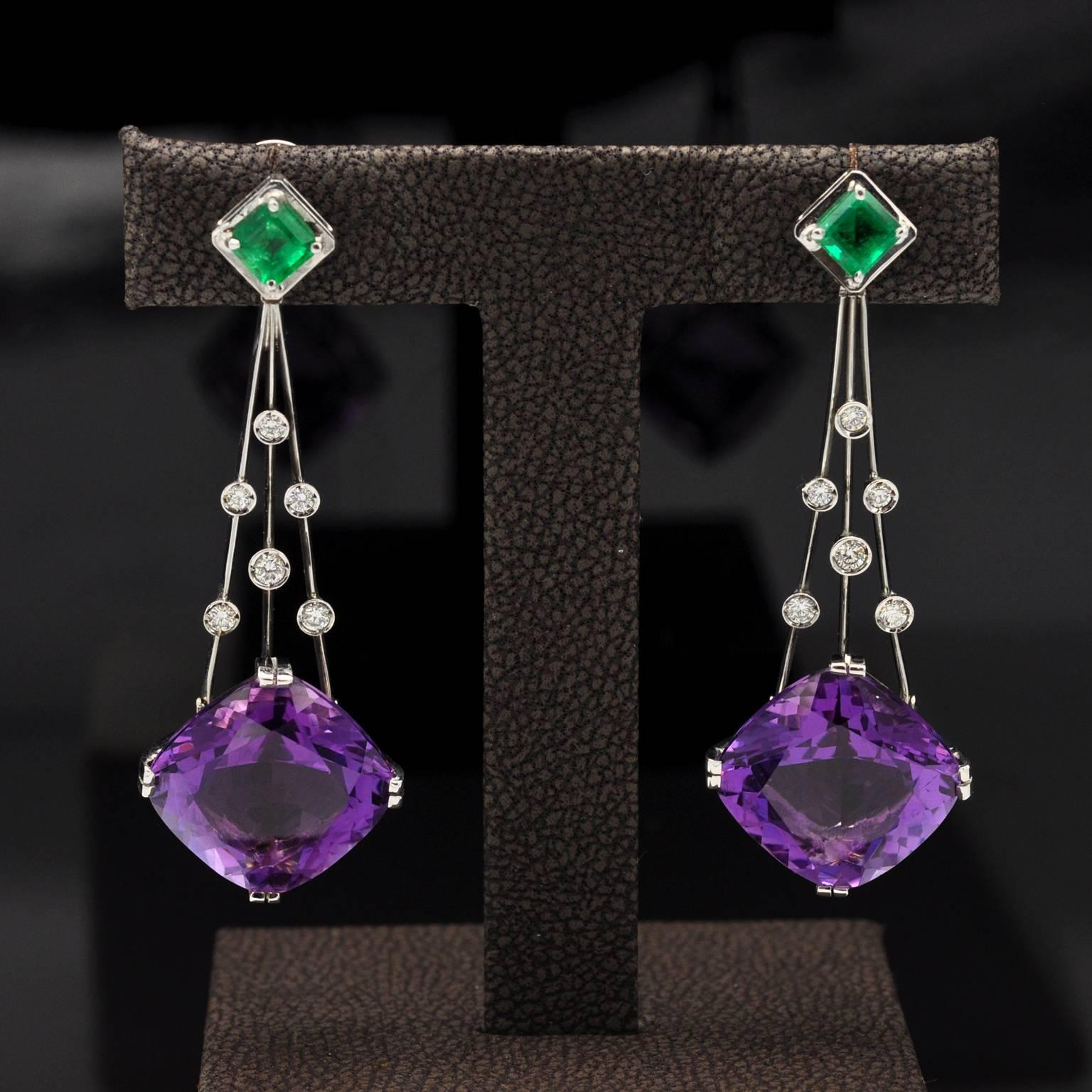 Stunning dangle Earrings set with two cushion shaped amethysts and two square Colombian emeralds. in between on three white gold lines, diamonds highlight the beauty of the piece like droplets on a web.

Amethyst : 24,73 Carats, Emeralds: 1,13