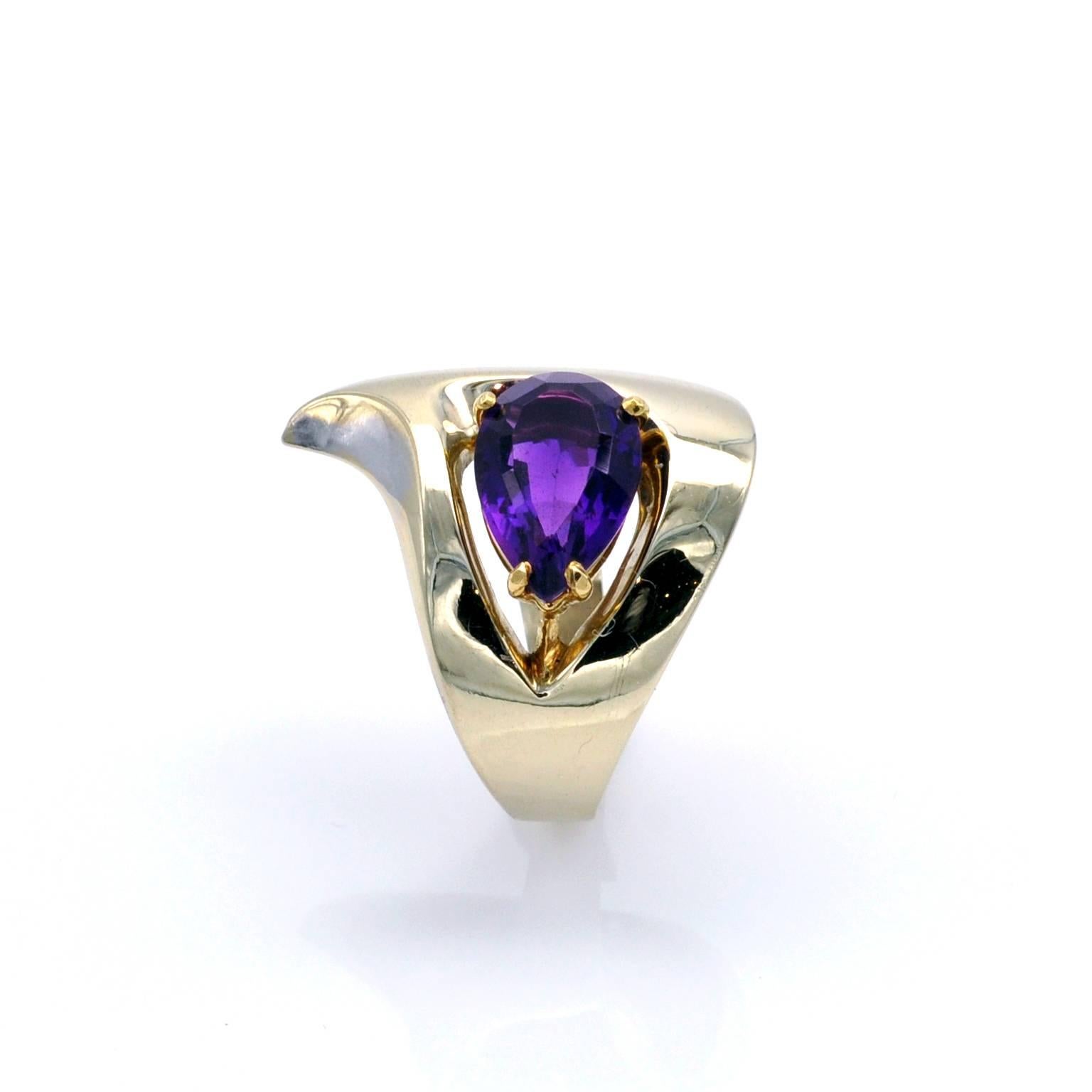 An Intense purple Amethyst is set in a yellow gold fitting which seems to float in in an opening of the asymmetric modern ring. The ring itself is in white gold unevenly rhodium plated so that , when you move  the ring, the color of the meta subtly