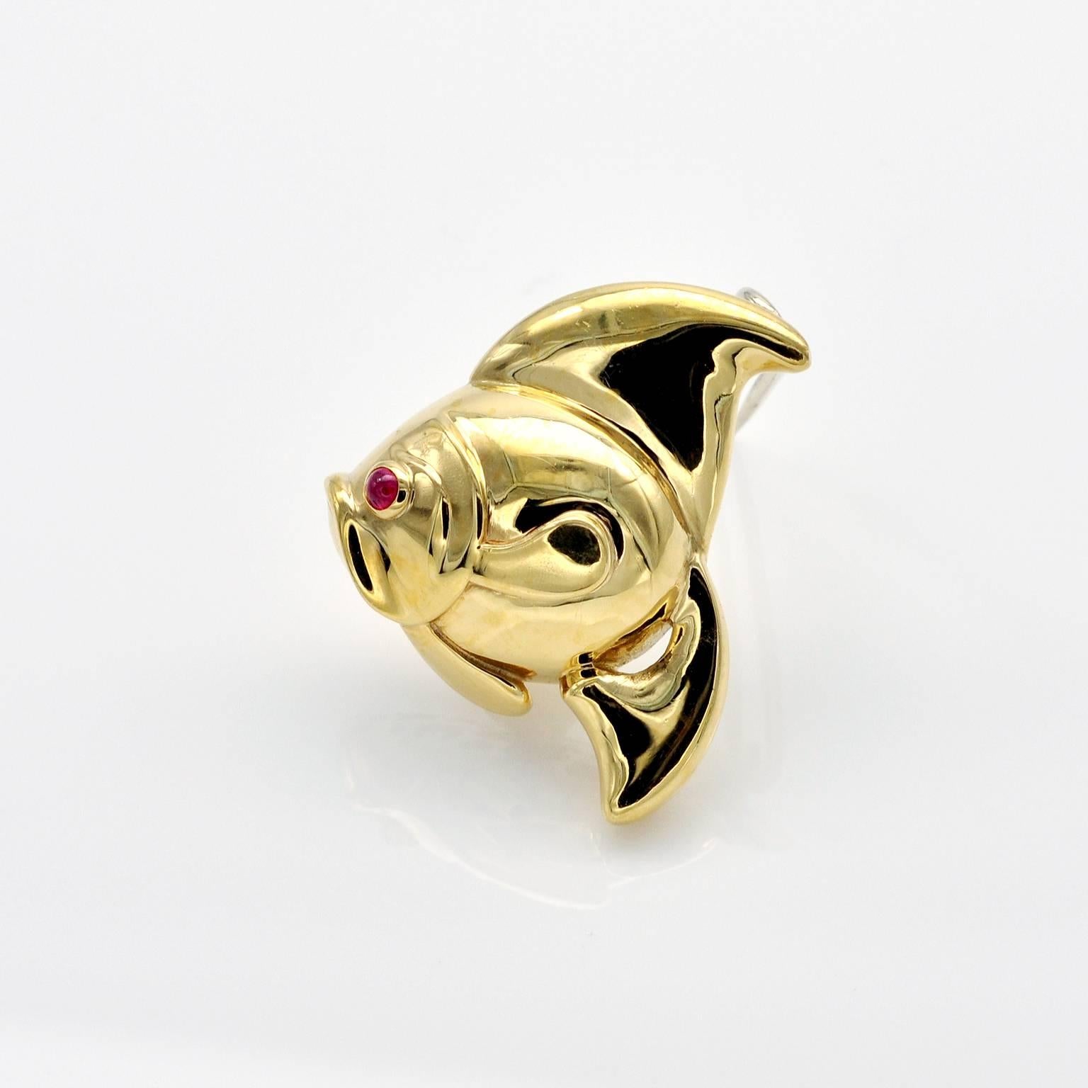Exquisite  brooch! the Fish is nice, rounded and... so precious!
The brooch is 18 kt gold with a round ruby cabochon for the eye. 
On the back hearts, stars and moons are cut in the gold lining.
Exquisite work.
French state hallmark .