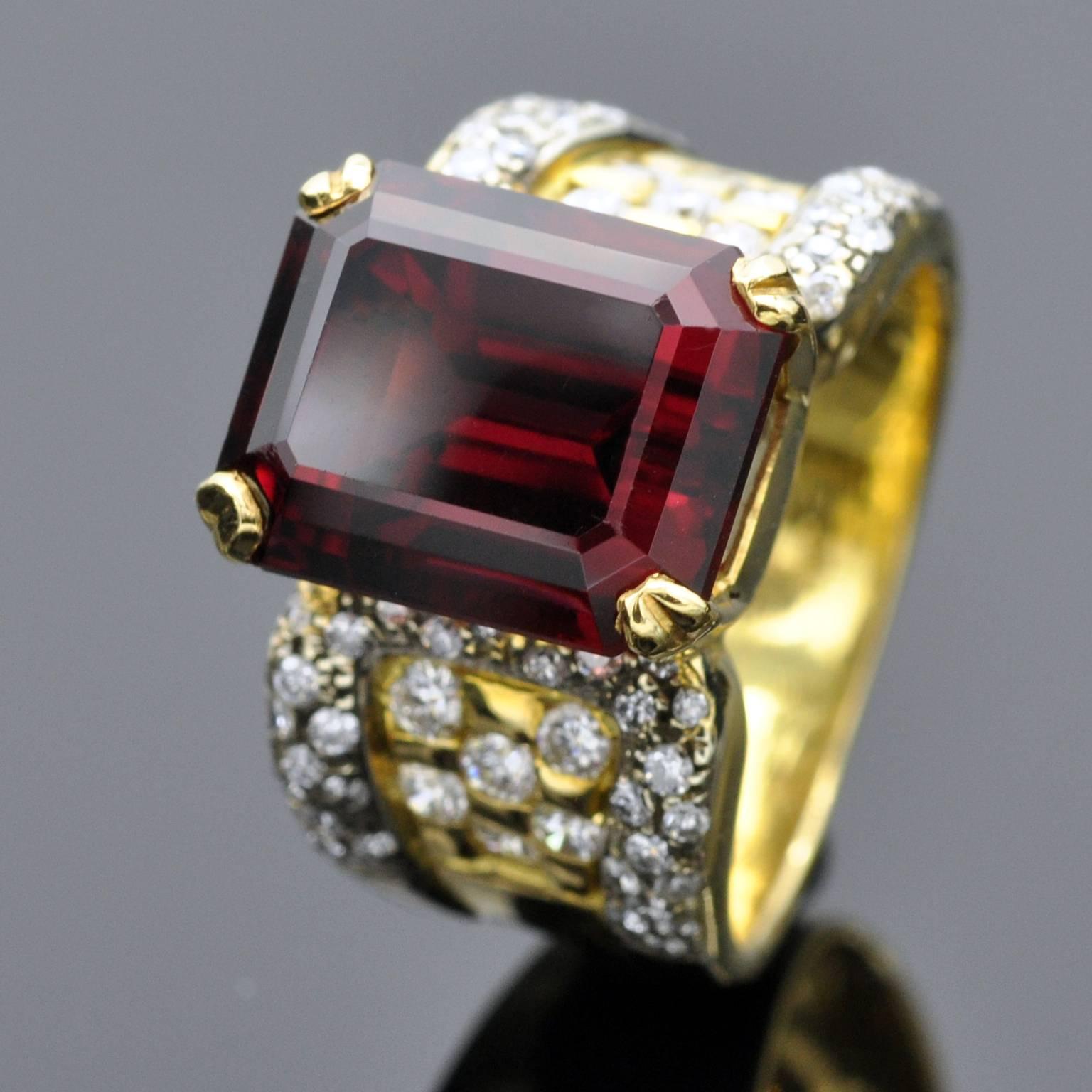 An emerald cut garnet prong set on a yellow and white gold cocktail ring. The garnet has has a dee rich purplish red color with a high brilliance, it weighs 10,40 carats. The diamonds: are approximately 1 carat, G VS .