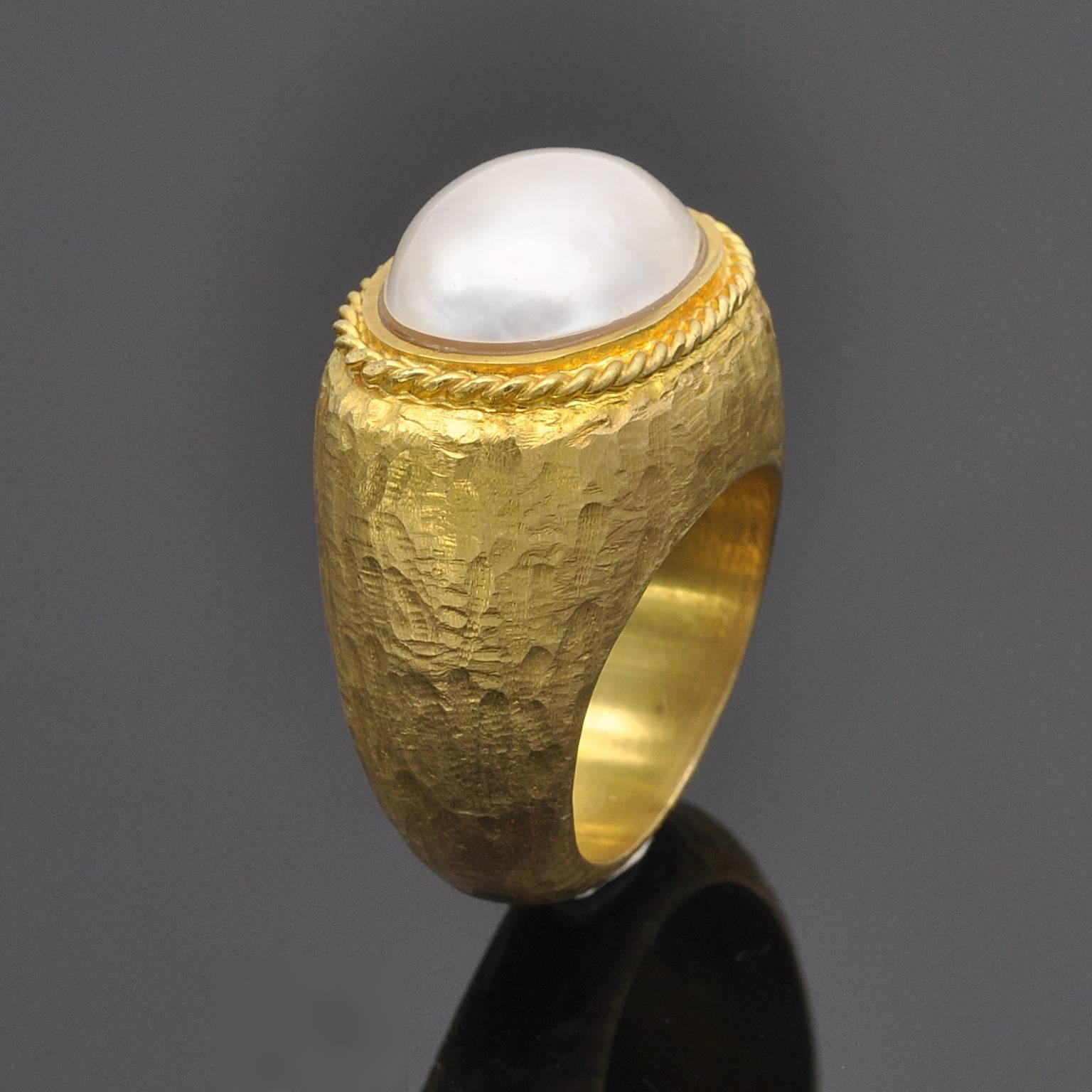 Gorgeous Ring which design was influenced by ancient greece. A large oval mabe ( 15x11mm ) pearl circled by "twisted rope " motif . The body of the ring is hammered 18KT yellow gold.