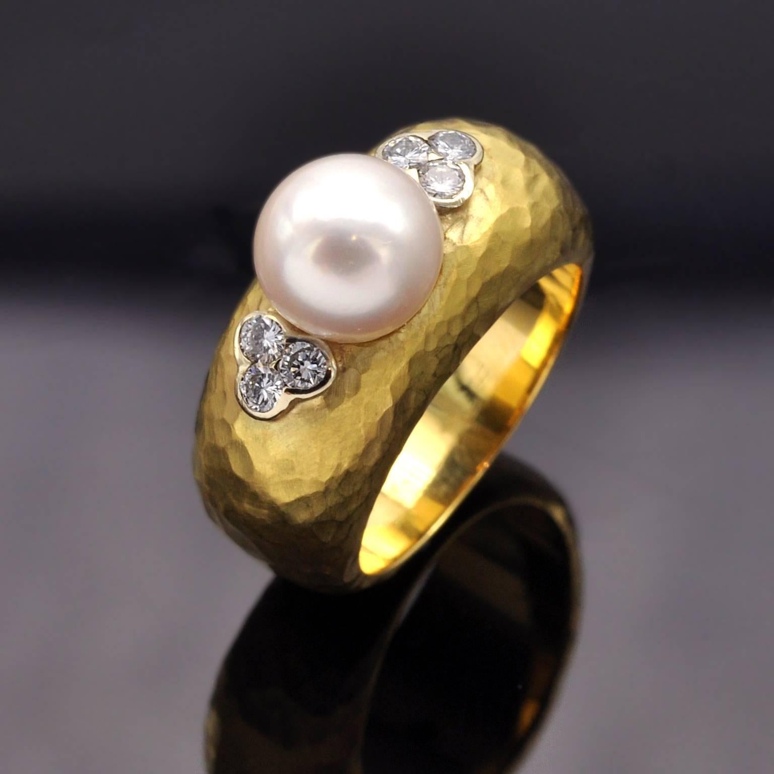Hand hammered 18kt gold gorgeous ring, with a 8.5mm round pearl in it center on each side of which 3 diamonds are set in a clover shaped white gold fitting.


