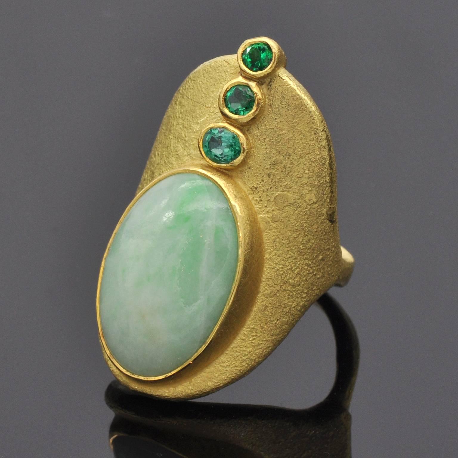 This unique modernist ring seems to get its ethnic inspiration from antique times. The jade (19.86 carat ) and three colombian emerald (0.49 carat)  are besel set . the ring itself is 18 and 22 Kt gold. 

Michael Zobel is considered one of the most