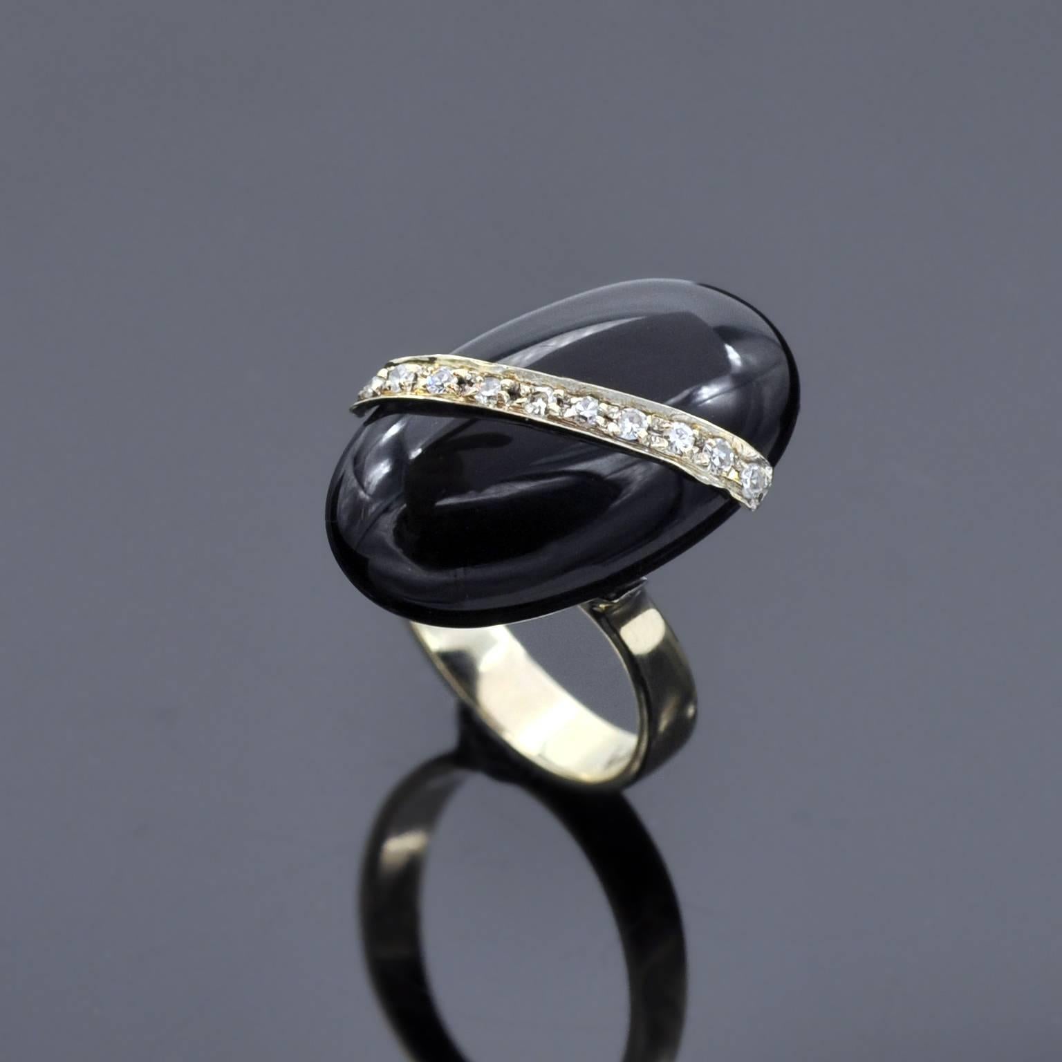 Unique design vintage cocktail ring ! a pebble like oval onyx on top of which a diamond set white gold lays in diagonal. 