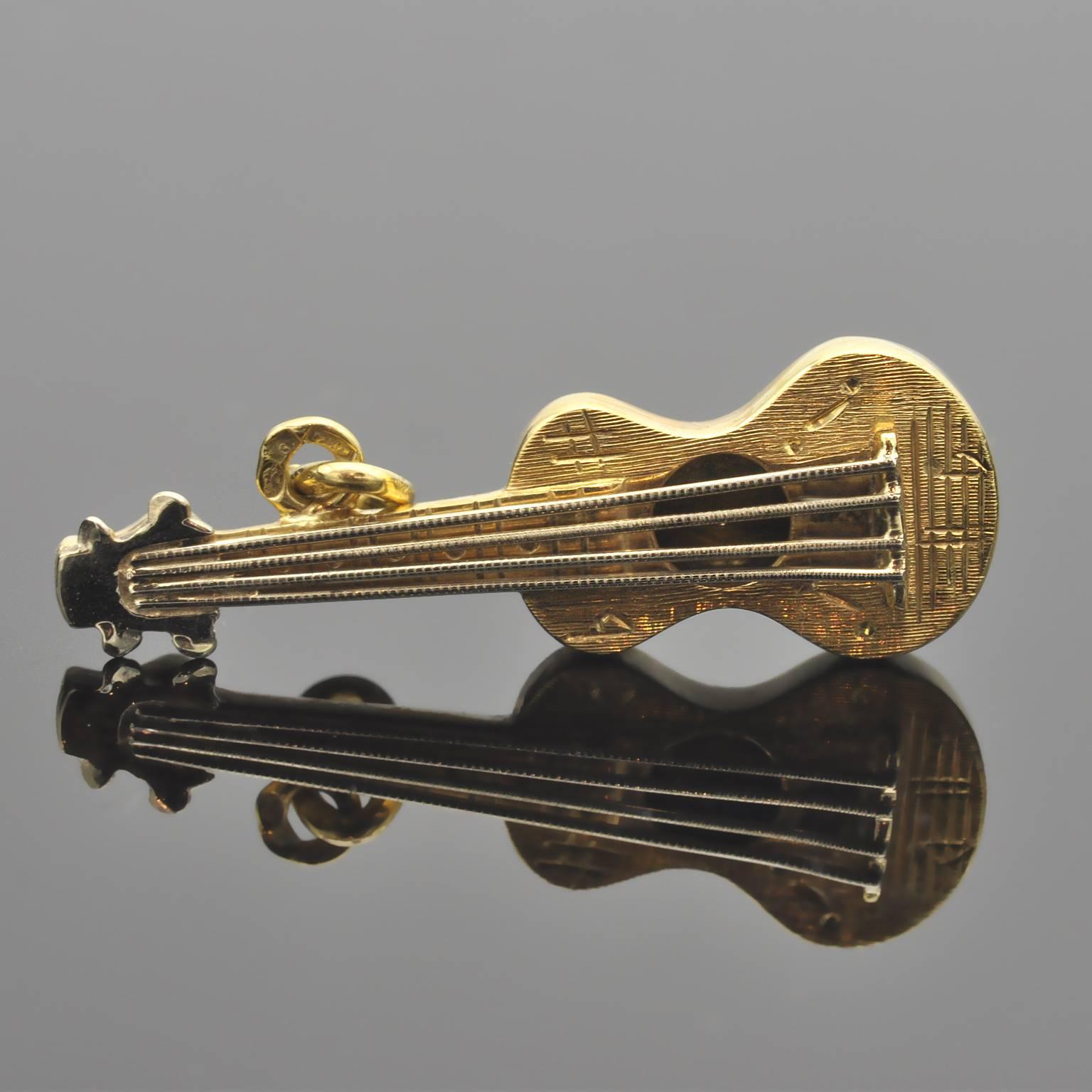 Exquisite 18 kt gold guitar pendant charm. The front is engraved with music notes while the back is polished. The guitar body is in yellow gold while the string and the head are in white gold.