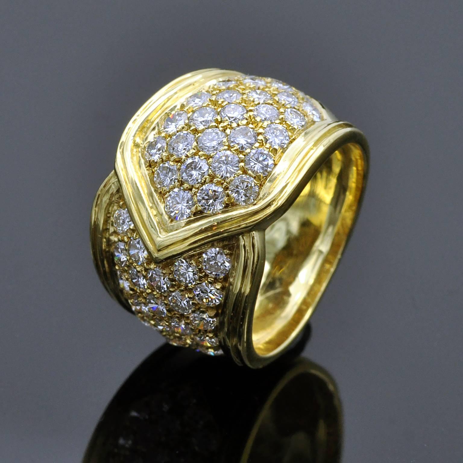
This statement ring features a wide band elegantly wrapped around the finger, reminiscent of a chevron design and subtly resembling a leaf. Crafted from 18k yellow gold, the ring is adorned with pavé-set white brilliant-cut diamonds, graded FG