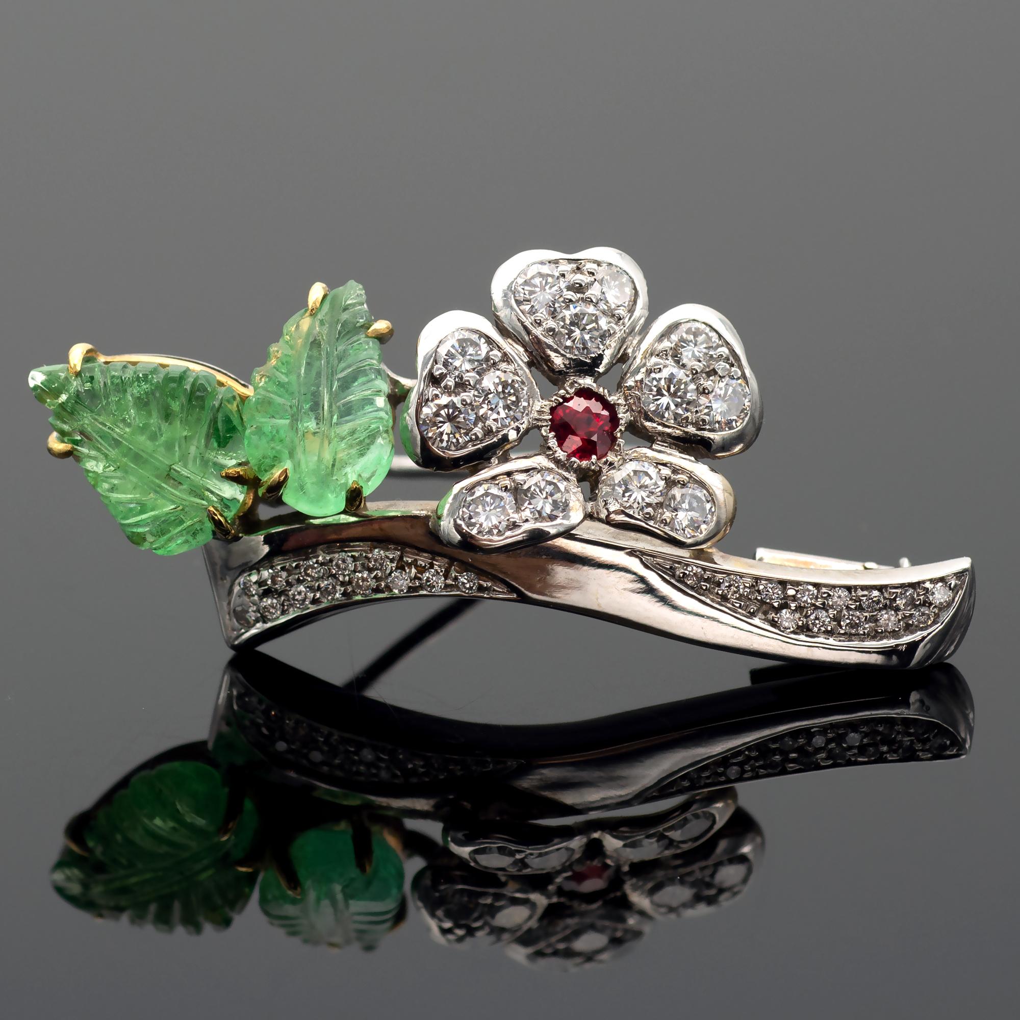 Exquisite floral gemstones and diamond brooch representing two engraved emeralds leaves and a flower on a branch all set in diamonds. The center of the flower is a lively intense red ruby. The make is excellent with a lot of attention to