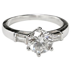 HRD-Ring mit drei Steinen: einem runden Diamanten (1,28 Karat, F, SI1) und zwei Baguette-Diamanten (je 0,24 Karat), aus 18-karätigem Weißgold.