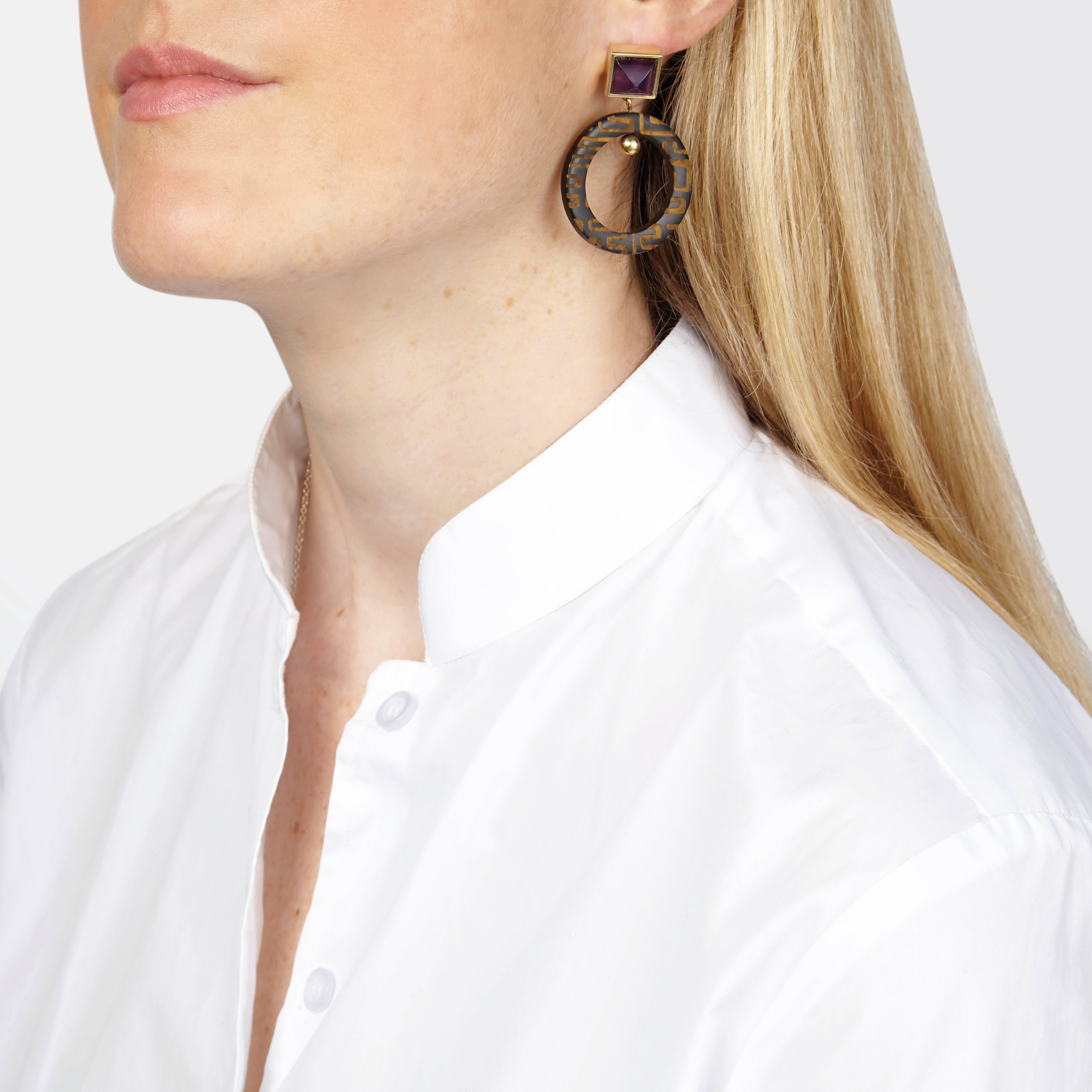 Earrings made of African cow horn and sugar-loaf shape amethyst. The engraving is inspired by West African Kuba textiles.

These engraved cow horn earrings are crafted by artisans in Kenya and finished by hand in London with solid silver pin-backs