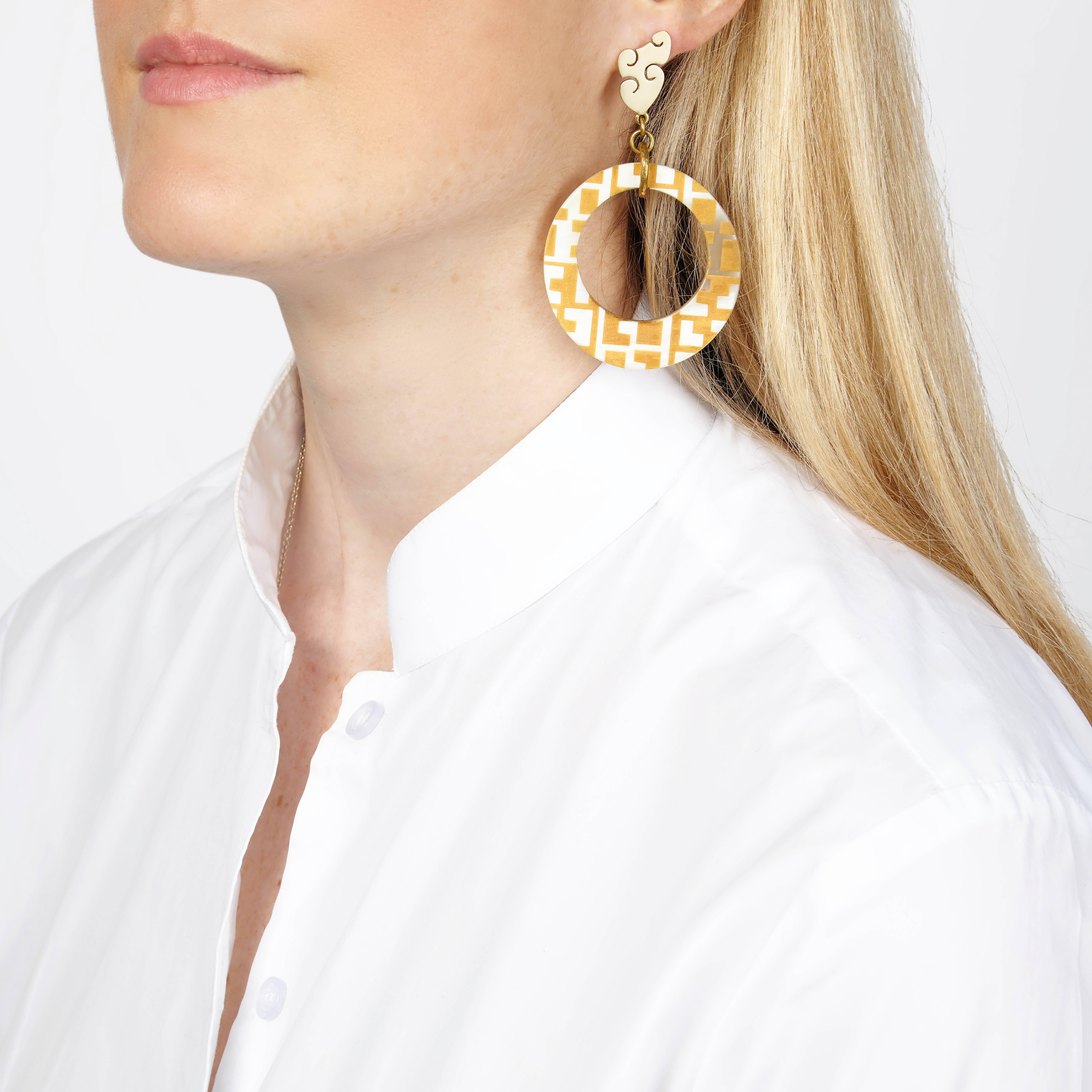 Hand crafted from African cow horn and finely engraved with a geometric design. The engraving reveals a light caramel color beneath the white cow horn. 

These statement earrings are crafted by artisans in Kenya, East Africa, and finished by hand to