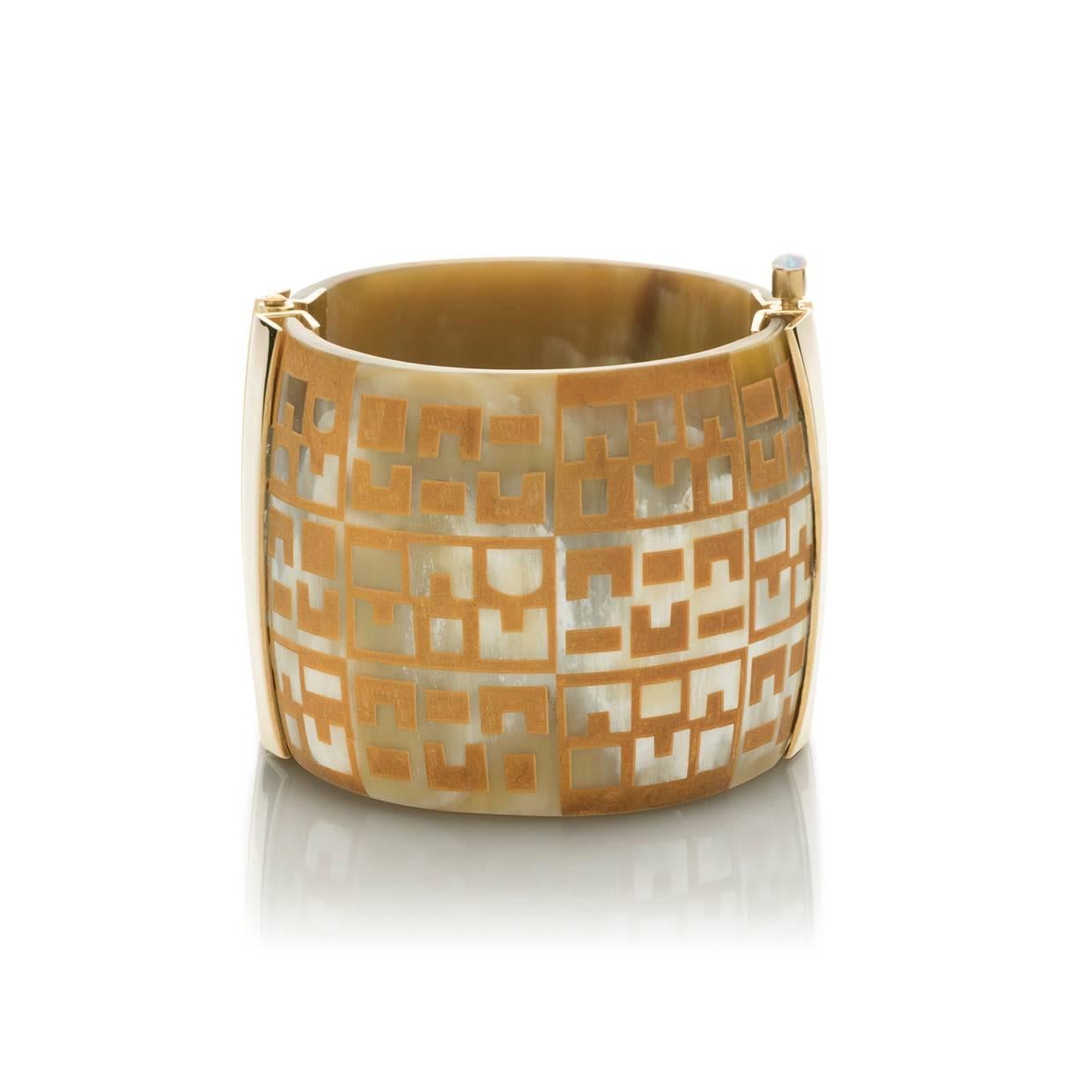 This unique cuff is handmade from African cow horn and engraved with African textile inspired design. The intricate pin-clasp is set with Ethiopian fire opal. 

Hand carved by artisans in Kenya; finished to the finest quality by hand in London. Each