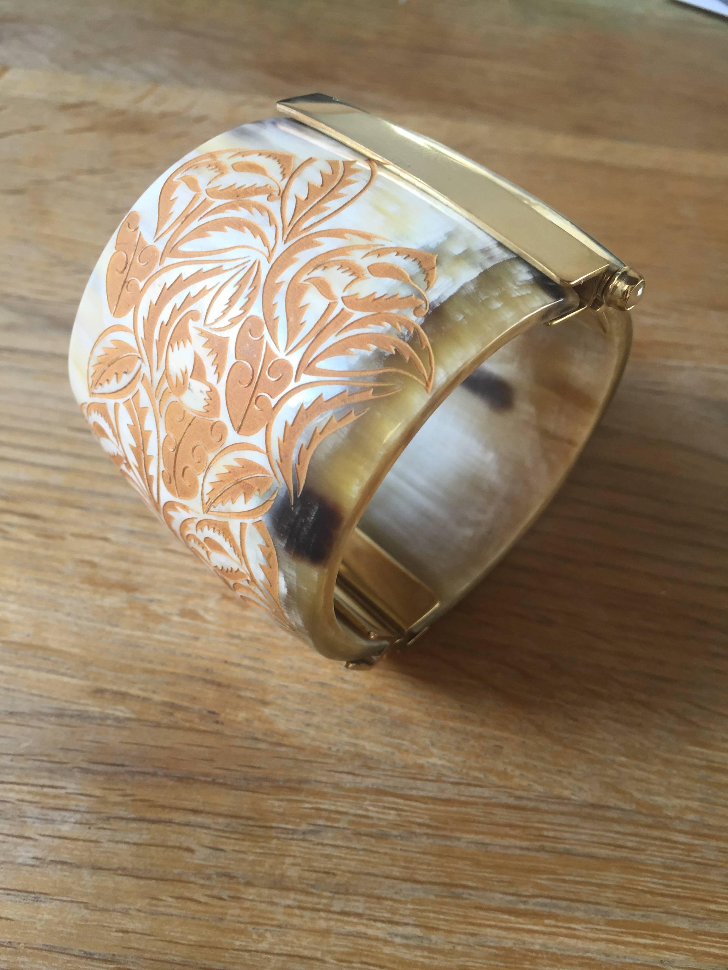 Cuff bracelet made of African cow horn engraved with wild foliage motif. The intricate pin-clasp is set with a  fire opal from conflict-free mines in Ethiopia. 

Hand crafted by artisans in Kenya, East Africa and finished to the finest quality by