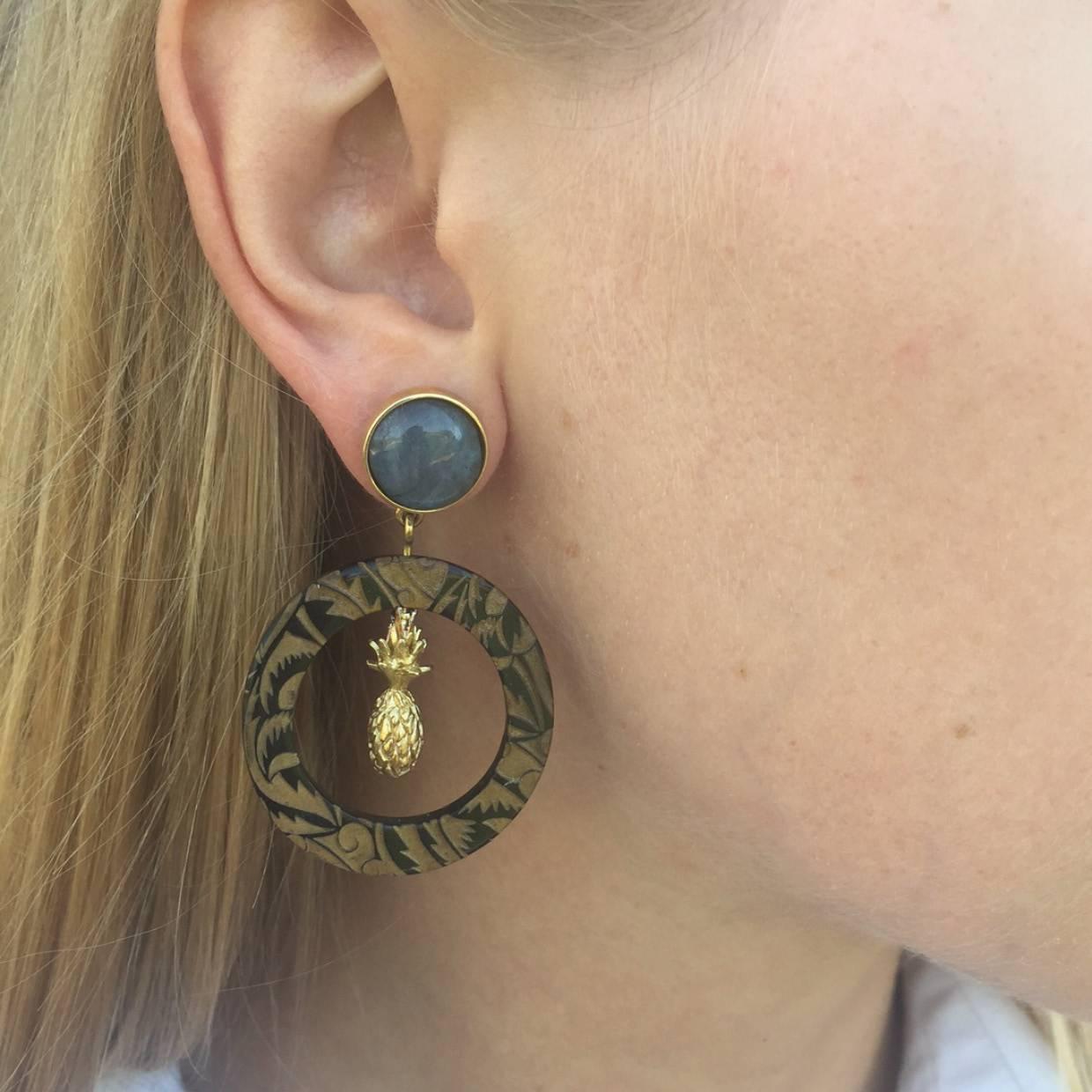 These engraved African cow horn hoops are set with the finest labradorite gemstone in a blue-gold color; sourced from ethical mines in Madagascar, Africa. 

Crafted by artisans in Kenya and finished by hand in London with solid silver pin-backs for