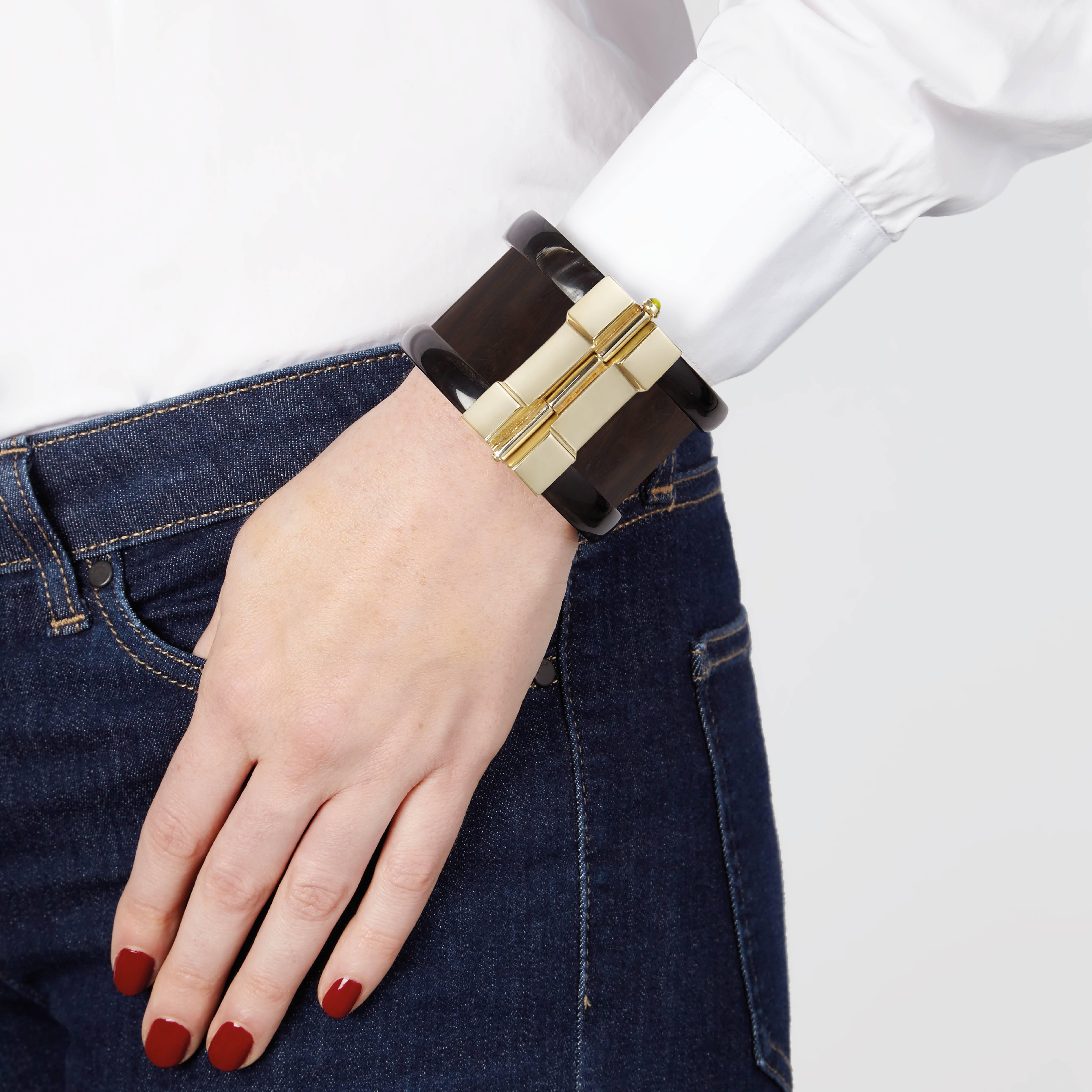 Cuff bracelet crafted by hand from ebony wood and African cow horn. The customizable 18k gold plate pin-clasp is set with choice or ruby or emerald. Inspired by warrior style cuffs worn by former Vogue editor Diana Vreeland. 

Each cuff is handmade