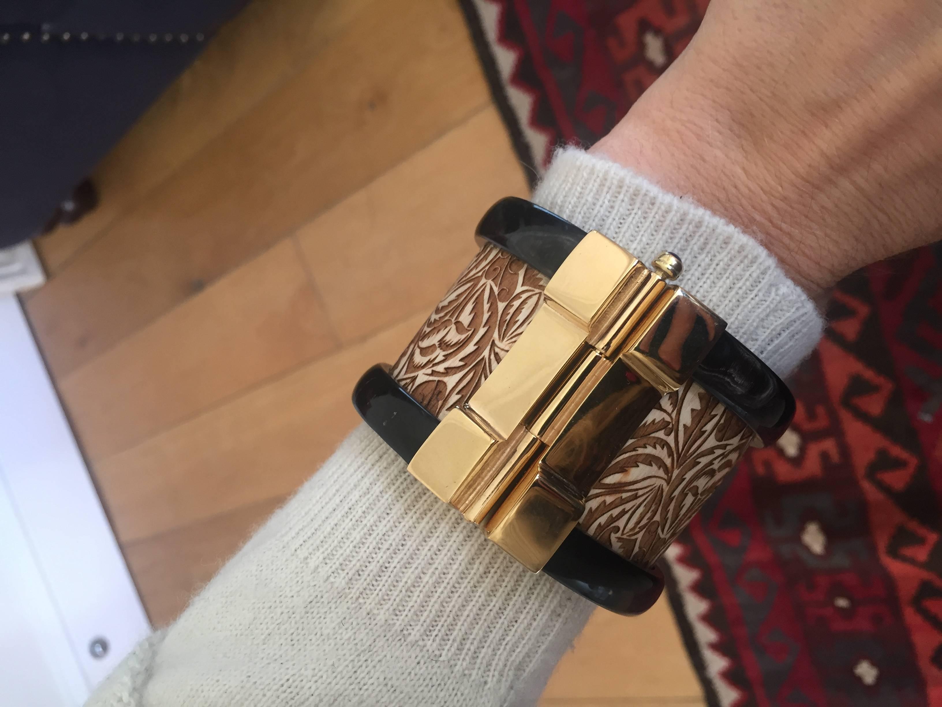 This bespoke cuff bracelet is crafted from engraved jacaranda wood and African cow horn. The intricate 18k gold plated pin-clasp is set with a blue sapphire. Inspired by warrior style cuffs worn by former Vogue editor Diana Vreeland. 

Each cuff is