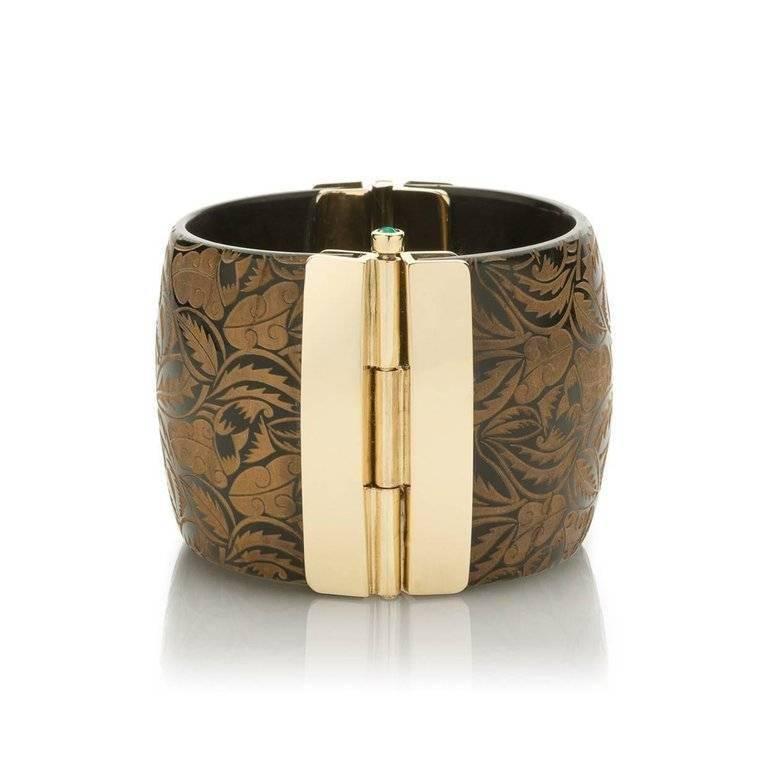 Cuff bracelet crafted by hand from African cow horn with engraved floral motif. The intricate pin-clasp is set with emerald.

This unique piece is available to ship immediately.  Each Fouché jewel is handmade from natural materials. Please note that