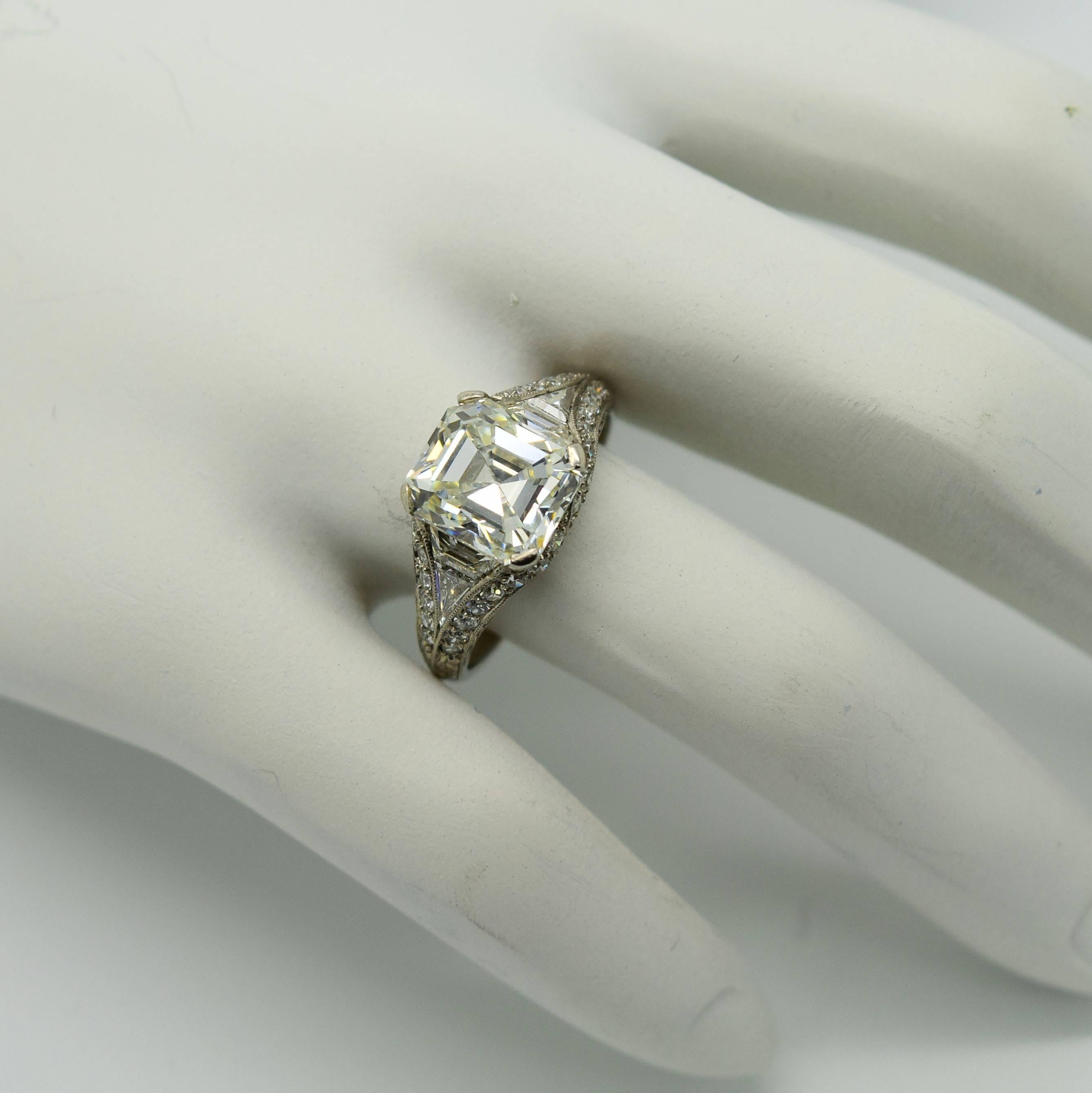 This is an exquisite Bailey Banks and Biddle Art Deco emerald cut diamond platinum filigree engagement ring from 1927. The center old emerald cut diamond weighs approximately 2.70cts. The side antique trapezoid, trillion and single cut diamonds