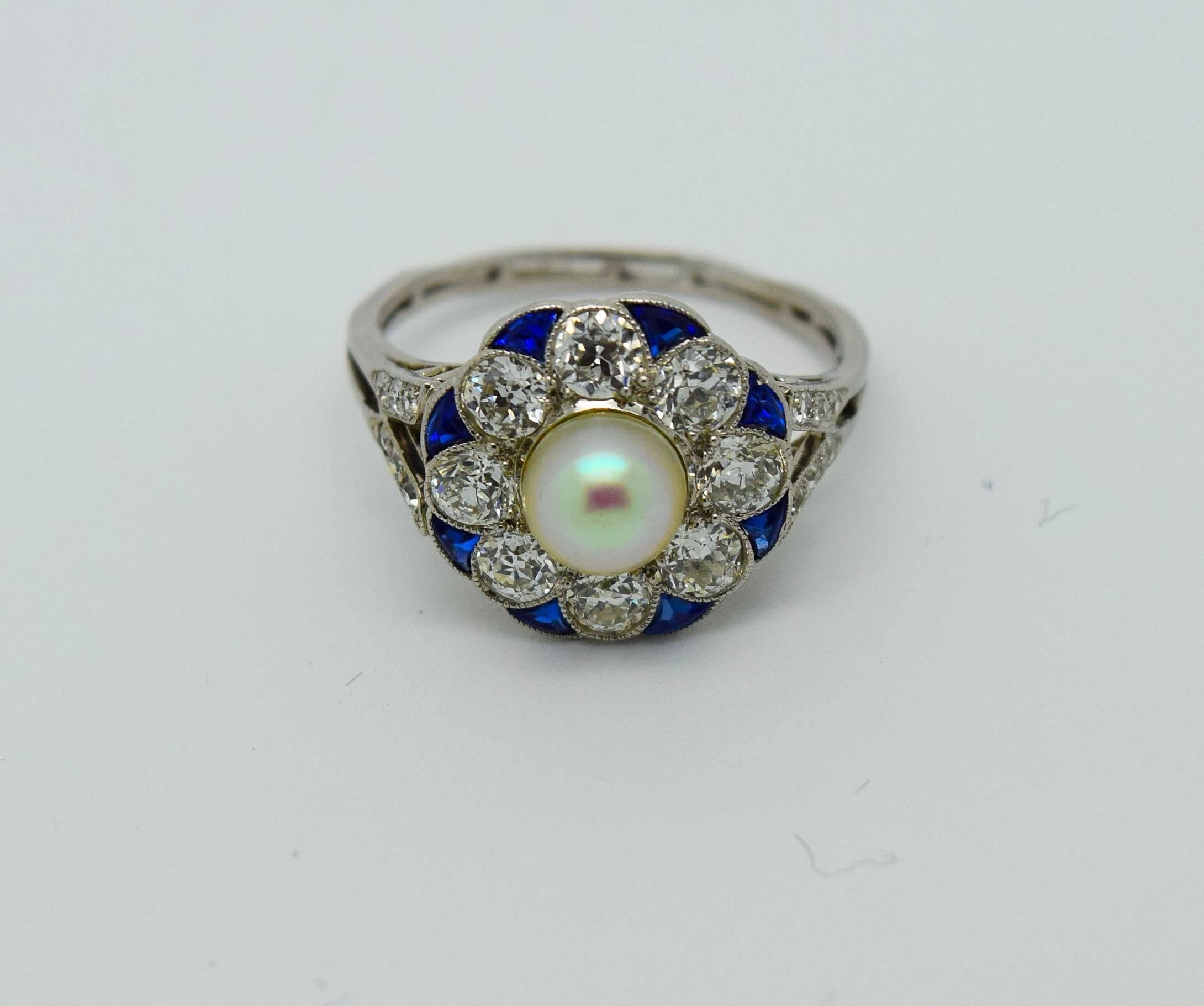 A gorgeous example of the Art Deco period, this ring features a pearl (possibly natural, origin unknown), old European cut diamonds, gorgeous calibrated blue sapphires, and is set in platinum. The diamonds weigh approximately 1.5cttw and are F-G in