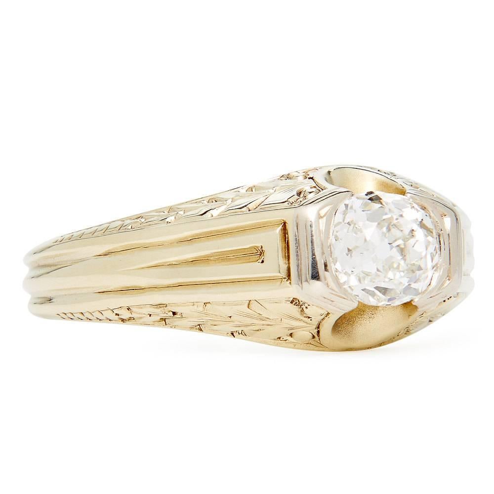 A fantastic art deco period diamond solitaire ring in 14 karat yellow gold and platinum. Set with a single old Mine cut diamond of 1.12 carats, this ring features wonderful hand engraving and hand carving work throughout in a traditional art deco