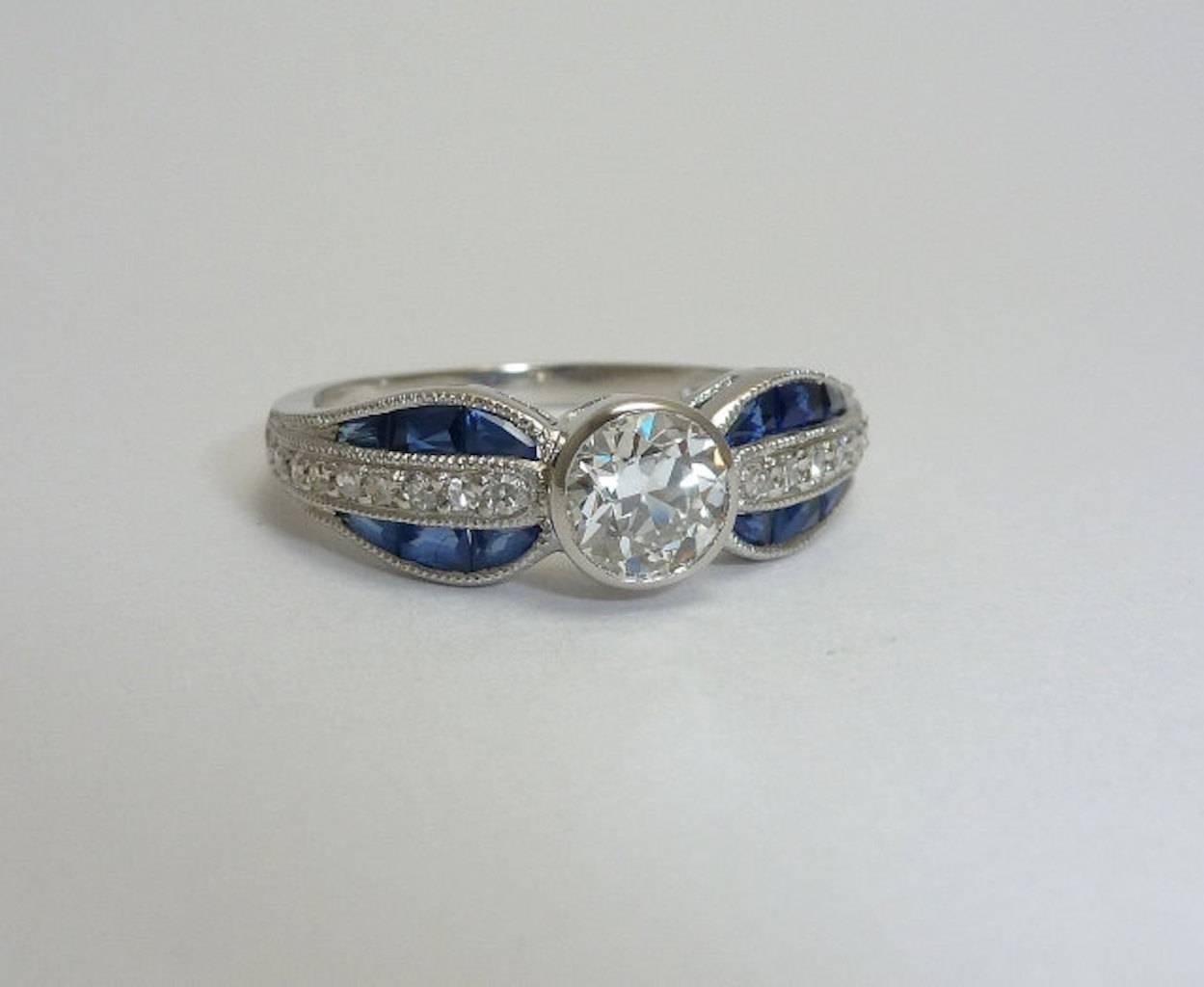 Beacon Hill Jewelers Presents:

A beautiful bow shaped diamond and sapphire ring in luxurious 900 fine platinum. Masterfully hand crafted, this stunning ring features a center bezel set diamond accented by custom cut French cut sapphires and