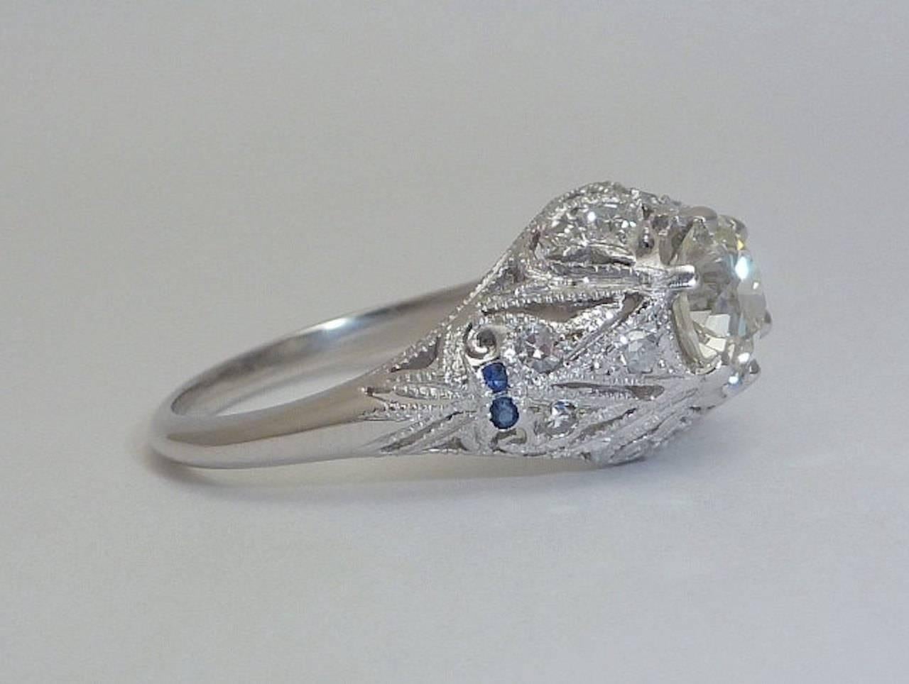 A stunning vintage Diamond and Sapphire engagement ring in luxurious platinum. Beautifully detailed this ring features incredible elaborate hand pierced filigree work, and mille grain beading~all completely hand done by a true master.

Centering