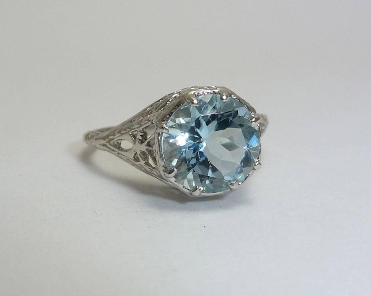 A stunning aquamarine filigree ring crafted in luxurious platinum. Centered by a single round substantial 8mm aquamarine, this stunning ring features beautiful pierced filigree work throughout complemented by beautiful hand engraving.

Weighing in