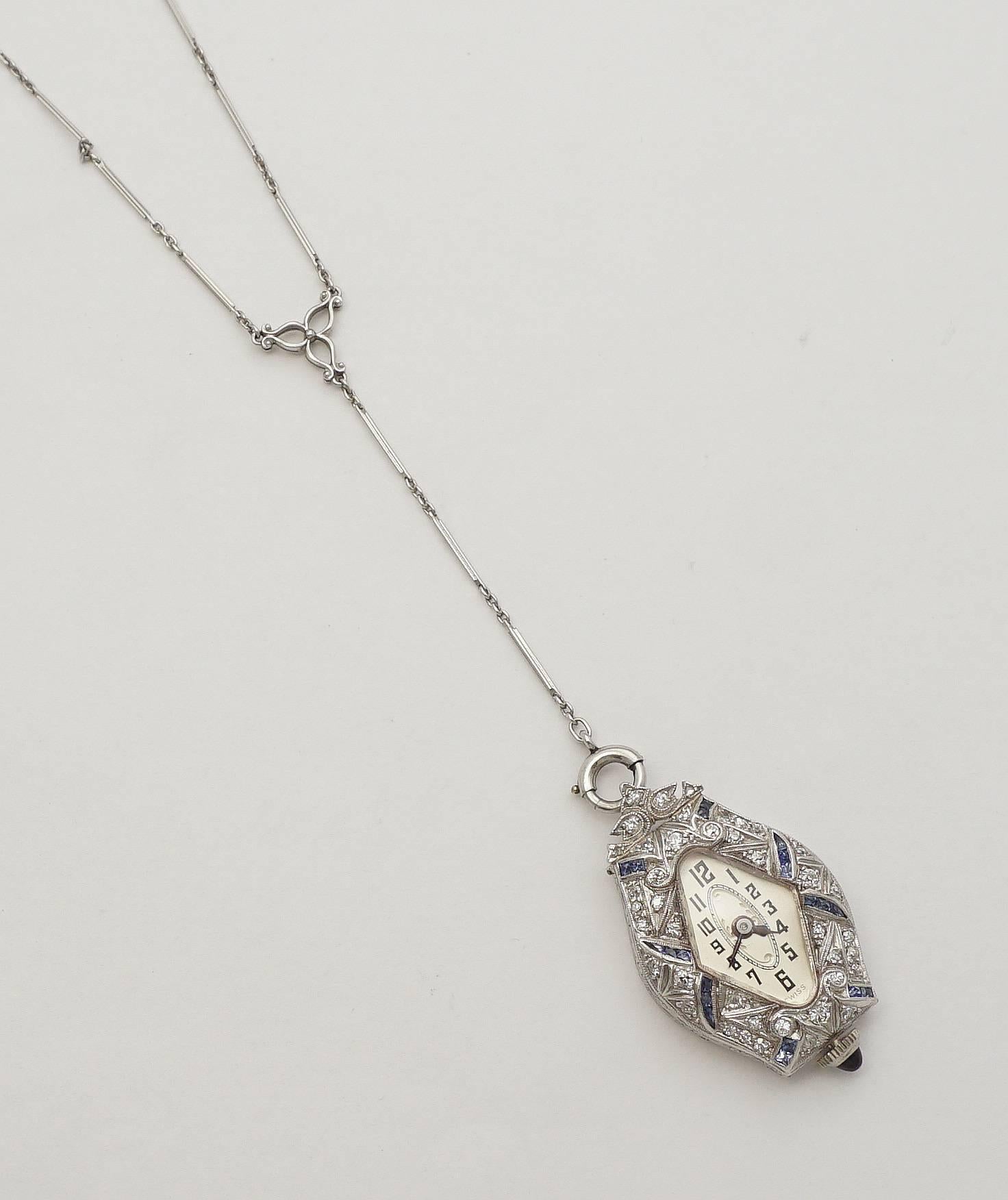 Beacon Hill Jewelers Presents:

A beautiful art deco period ladies pendant watch in platinum, adorned with French cut sapphires and European cut diamonds. Suspended from a beautiful original platinum bar link chain with a central floral medallion