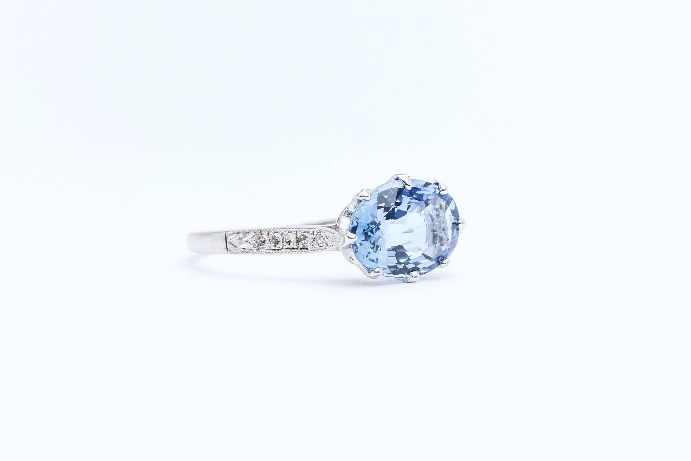 A beautiful sapphire and diamond ring in luxurious platinum. Centered by a fantastic vivid blue Ceylon sapphire this ring features a delightful hand crafted platinum mounting accented by ten pave set diamonds, and beautiful hand engraving.

Of