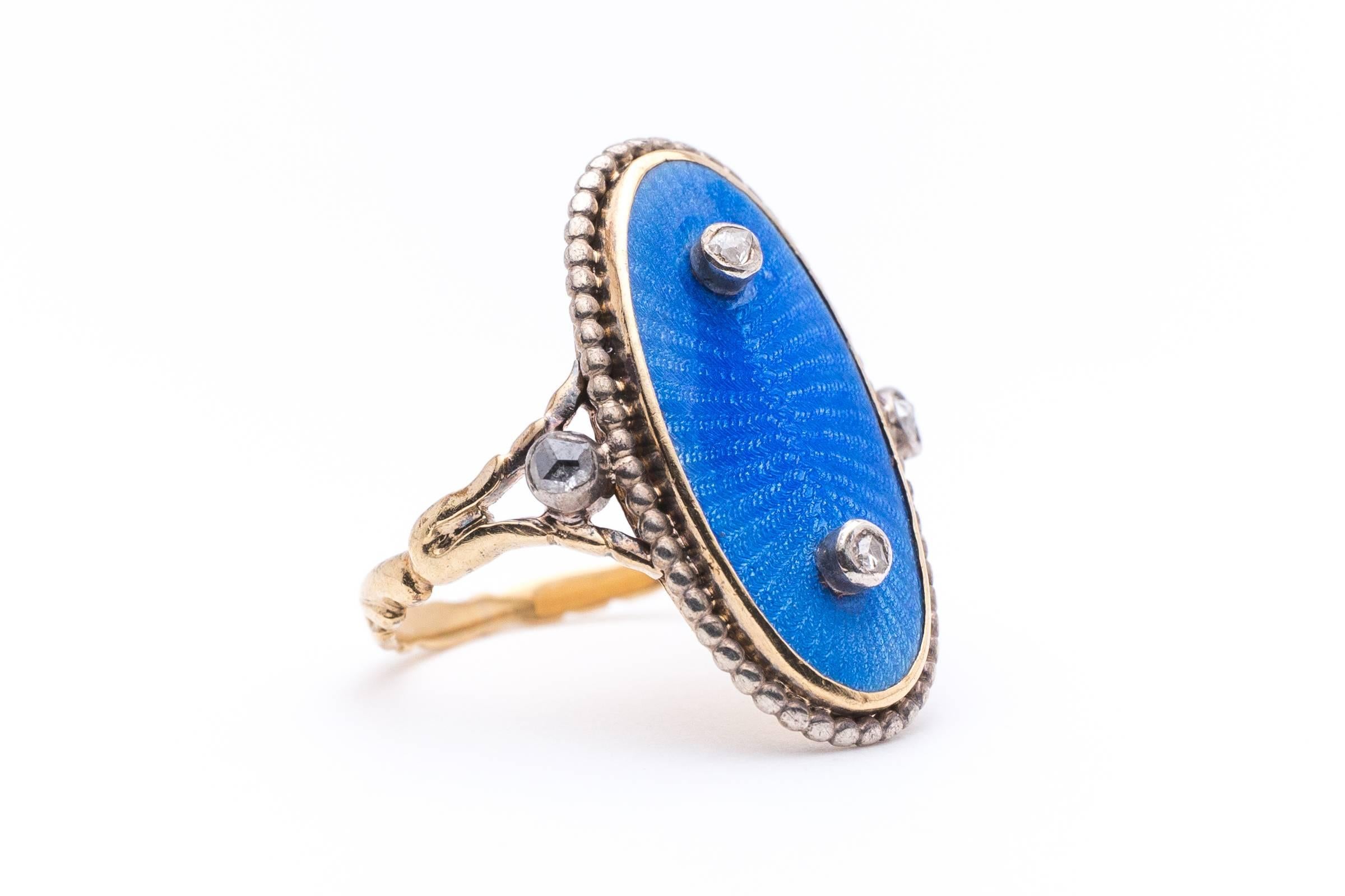 Beacon Hill Jewelers Presents:

A beautiful blue enameled plaque ring in tested yellow gold and silver. Featuring a center oval guilloche enameled plaque measuring an overall 20mm and accented by two silver bezel set rose cut