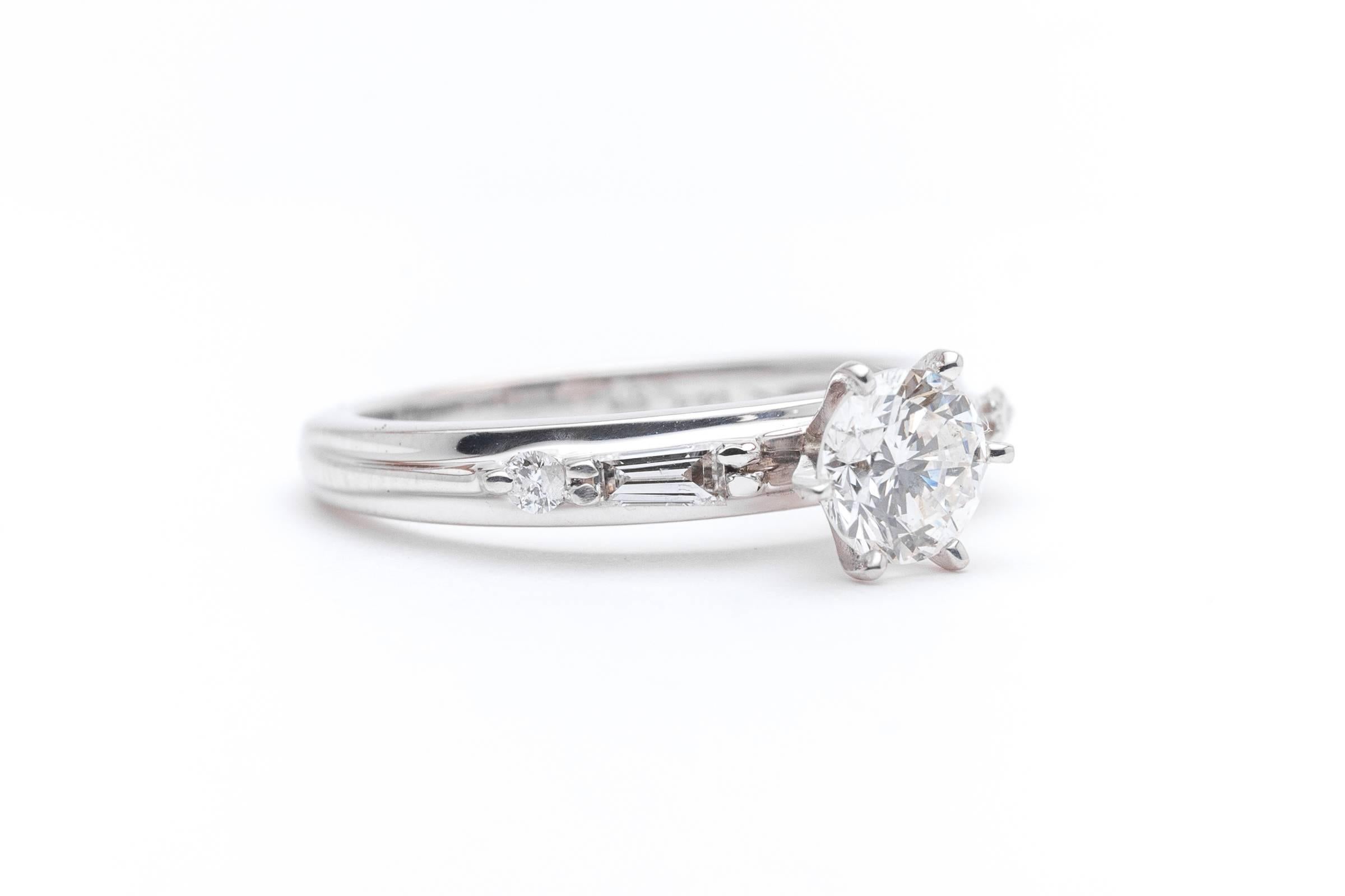 A timeless contemporary diamond engagement ring suite in 14 karat white gold. Centered by a 0.75 carat round brilliant cut diamond this ring features accenting baguette and brilliant cut diamonds along with a matching white gold wedding