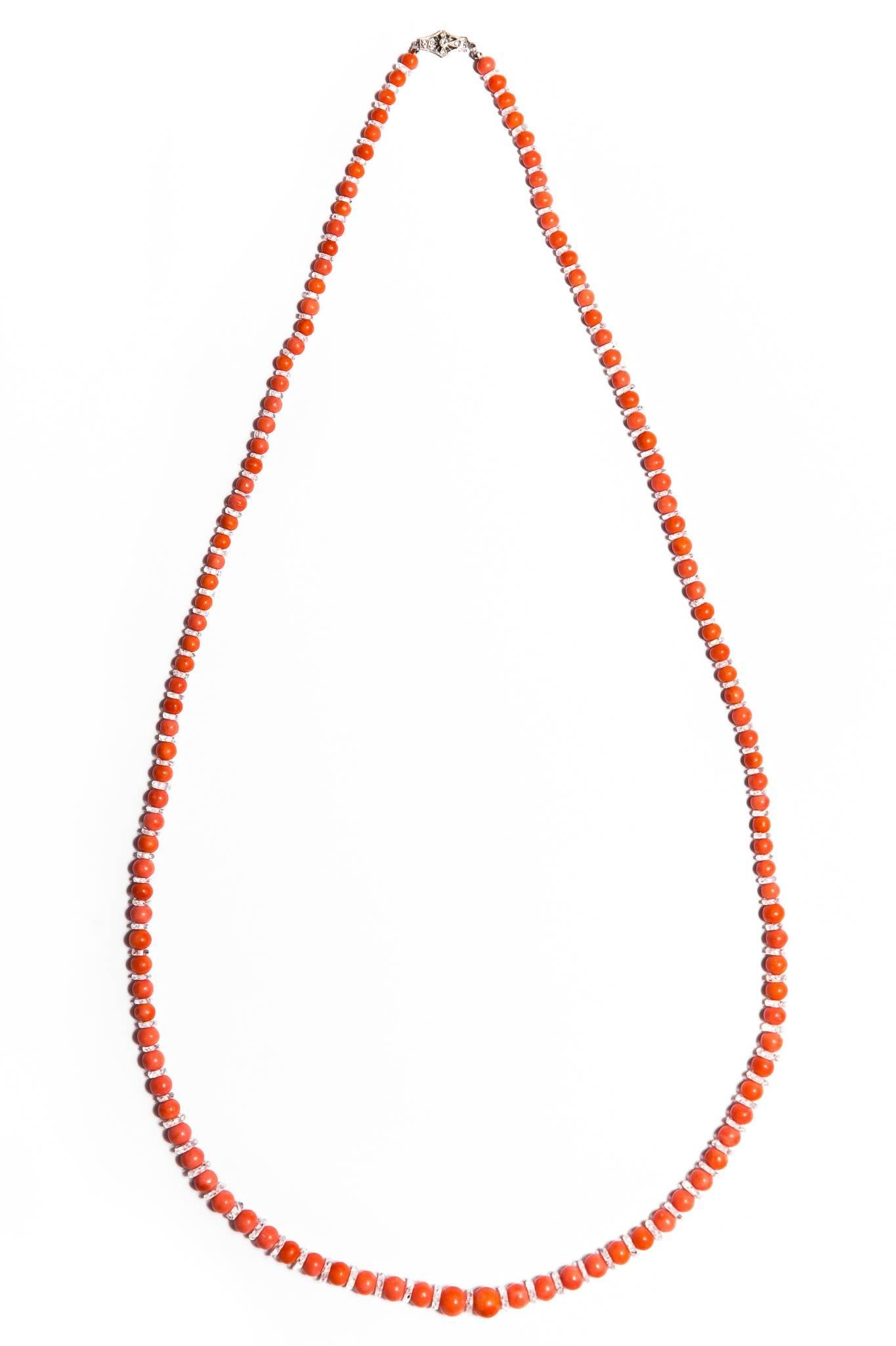 A beautiful art deco period natural coral and rock crystal opera length necklace with a platinum and diamond clasp. Featuring alternating round natural coral beads and faceted rock crystal disks, this necklace also boasts a platinum and diamond