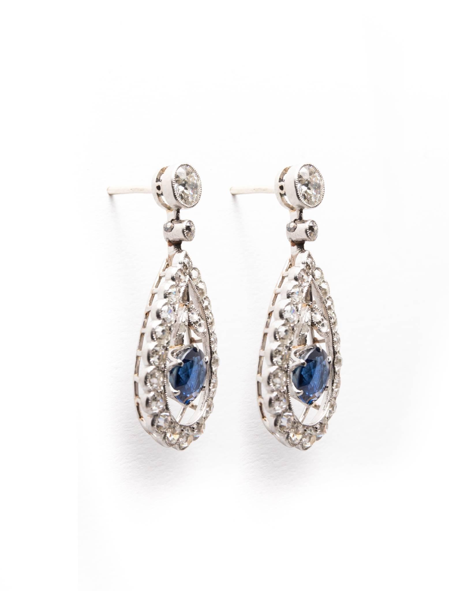 A truly fantastic pair of edwardian period sapphire, and diamond earrings in luxurious platinum.  Featuring a bezel set diamond at the top followed by dangling vivid blue sapphires encircled by diamonds these are truly a stunning pair of traditional