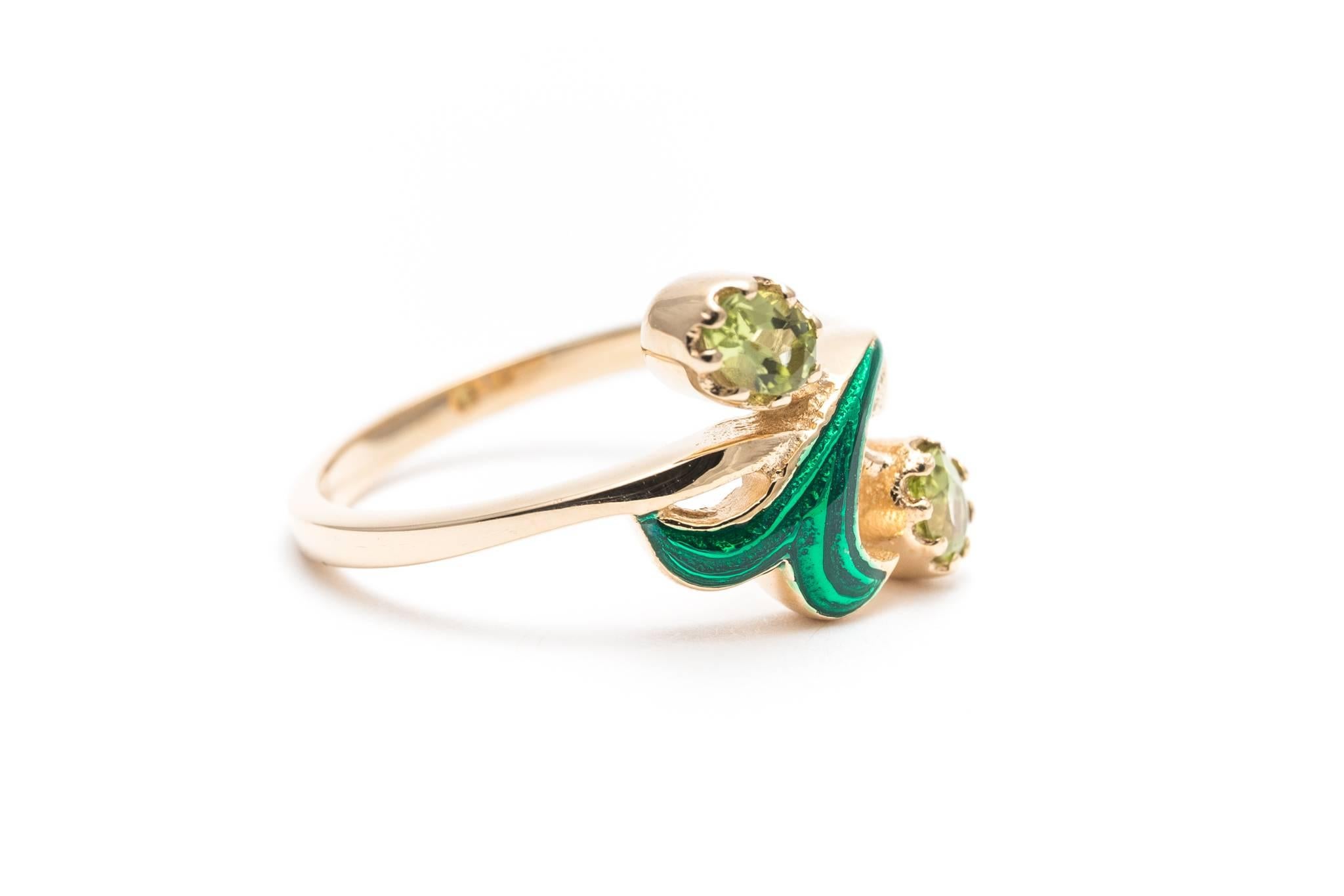 A beautiful flower form peridot and enamel ring in yellow gold.  Featuring a rich green enameled flower framed by peridot petals this ring is a superb example.

Of beautiful VS clarity and vivid green color the two matching cushion shaped peridot