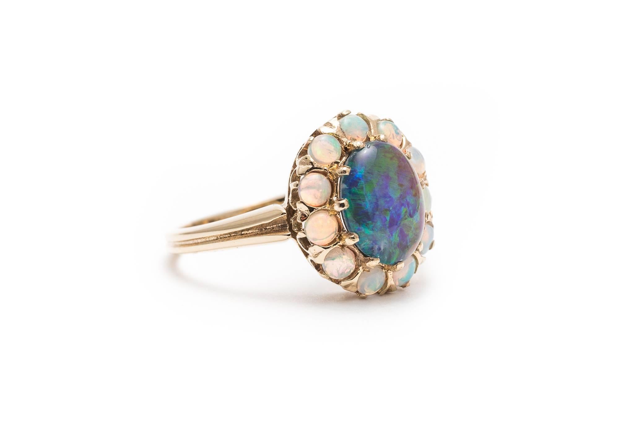Beacon Hill Jewelers Presents:

A beautiful opal ring in yellow gold.  Centered by a cabochon cut Lightning Ridge opal this ring features a halo of smaller white Australian opals surrounding the center opal.

Measuring 9mm in length by 7mm in width