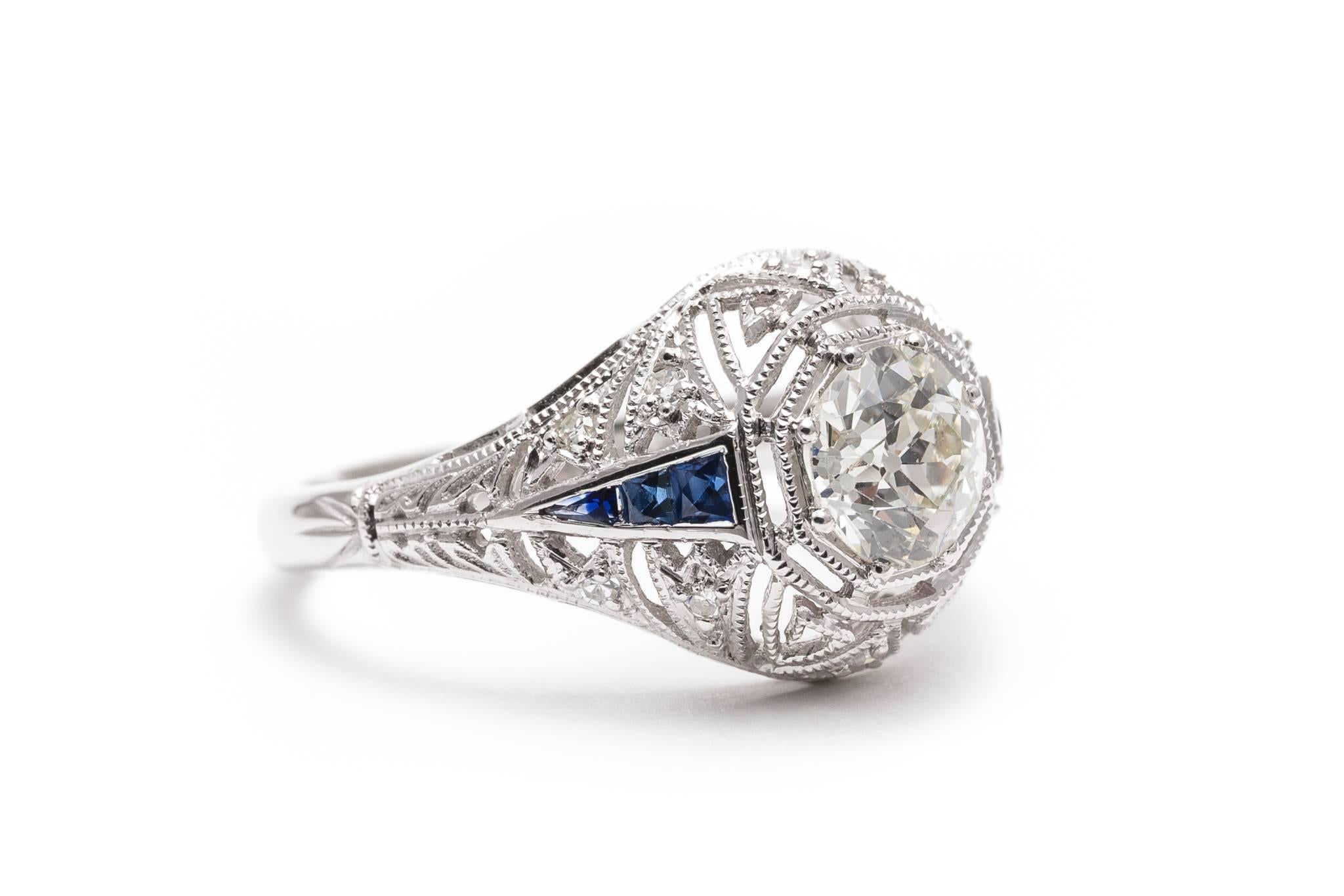 A fantastic a diamond and sapphire engagement ring in luxurious platinum.  Centered by a 1.03 carat antique European cut diamond this ring features a beautiful handmade filigree mounting complimented by rich French cut sapphires.

Of beautiful VS