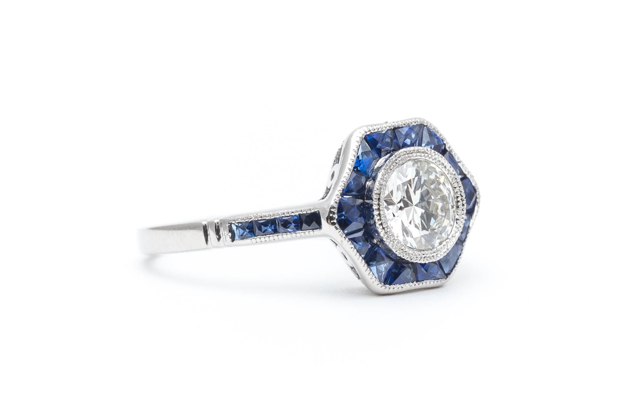 A beautiful hand crafted sapphire and diamond ring in luxurious platinum. Centered by a sparkling antique European cut diamond weighing 0.75 carats, this ring features a uniquely styled halo of bespoke French cut sapphires.

Designed as a flower