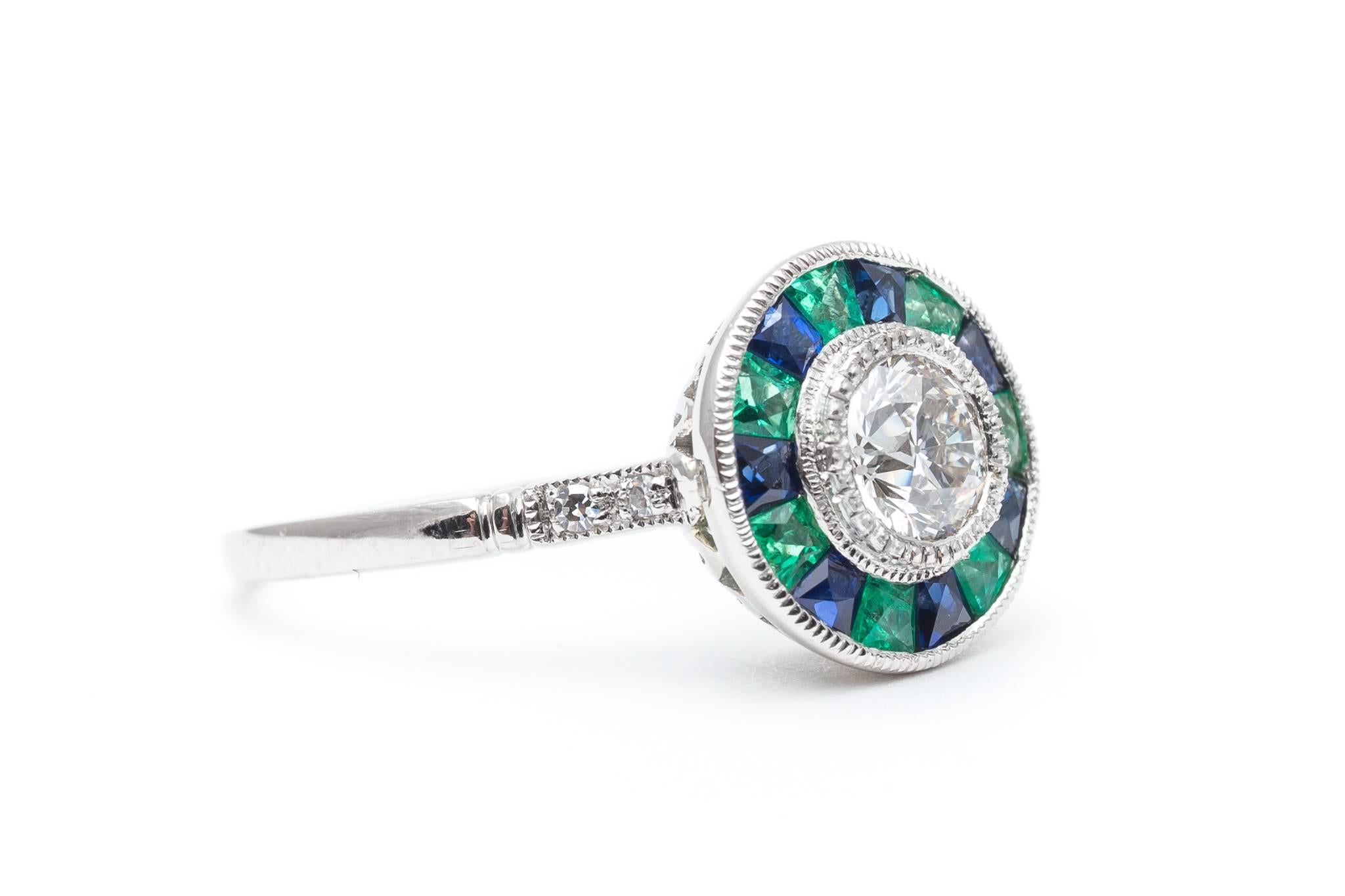 A truly special diamond, sapphire, and emerald target ring. Centered by a single bezel set antique European cut diamond weighing 0.52 carats this ring features alternating sapphires and emerald surrounding the center diamond for a truly unique look.