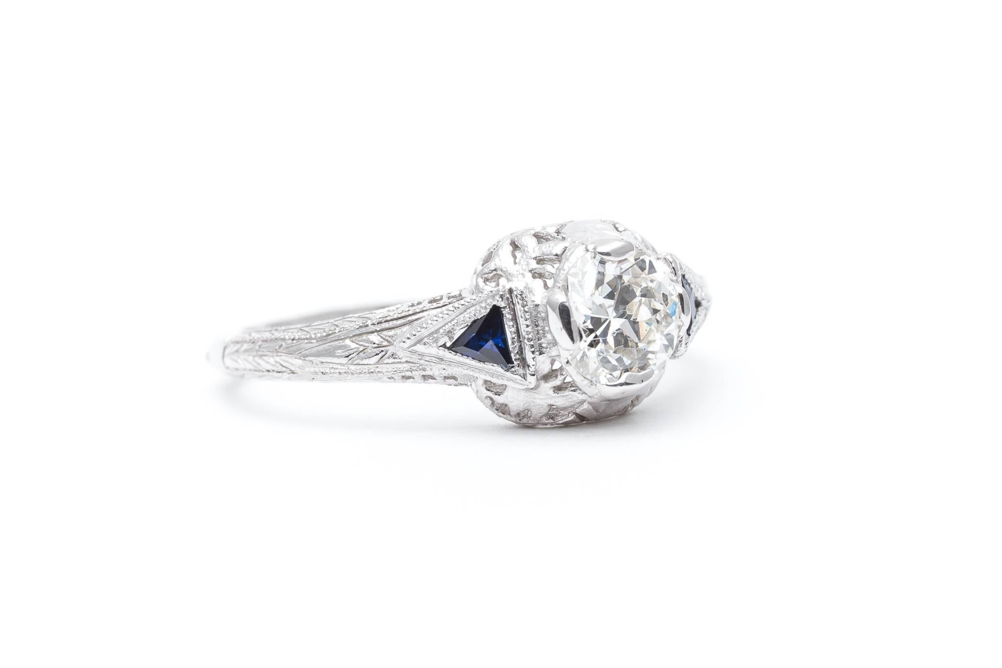 A beautiful hand engraved diamond and sapphire engagement ring. Centered by a sparkling 0.65 carat antique European cut diamond this ring features fantastic hand engraving and hand pierced filigree work throughout the mounting.

Secured by four