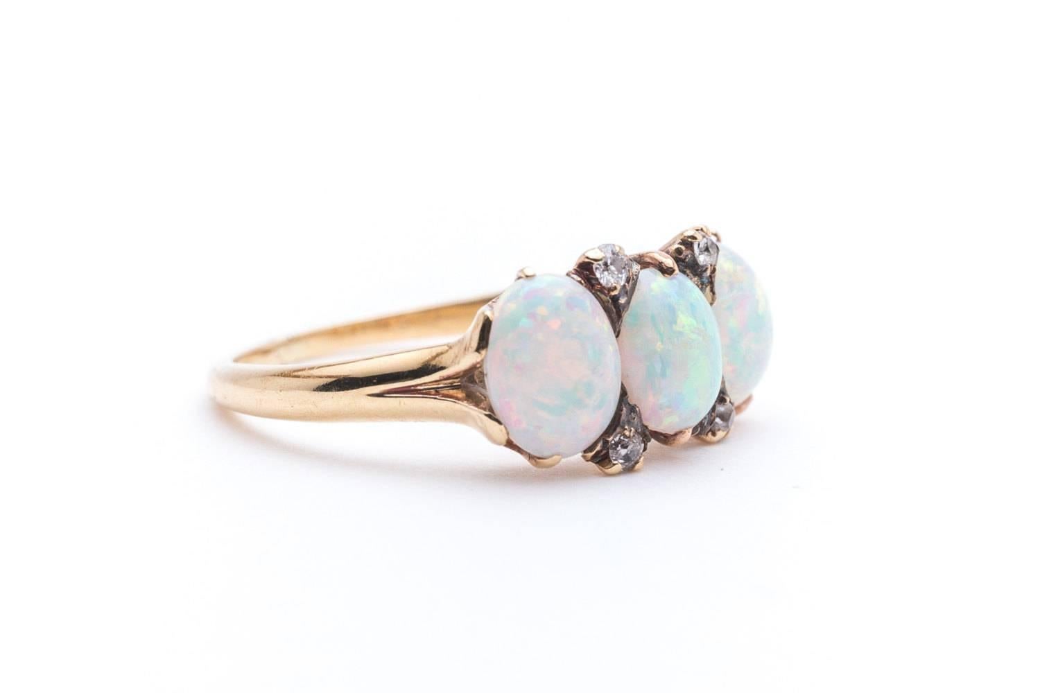 An antique victorian era opal and diamond ring in 18 karat yellow gold. Centered by a trio of perfectly matched natural Australian opals this ring features a hand crafted filigree mounting.

Of beautiful vivid color, the opals feature a blue ground
